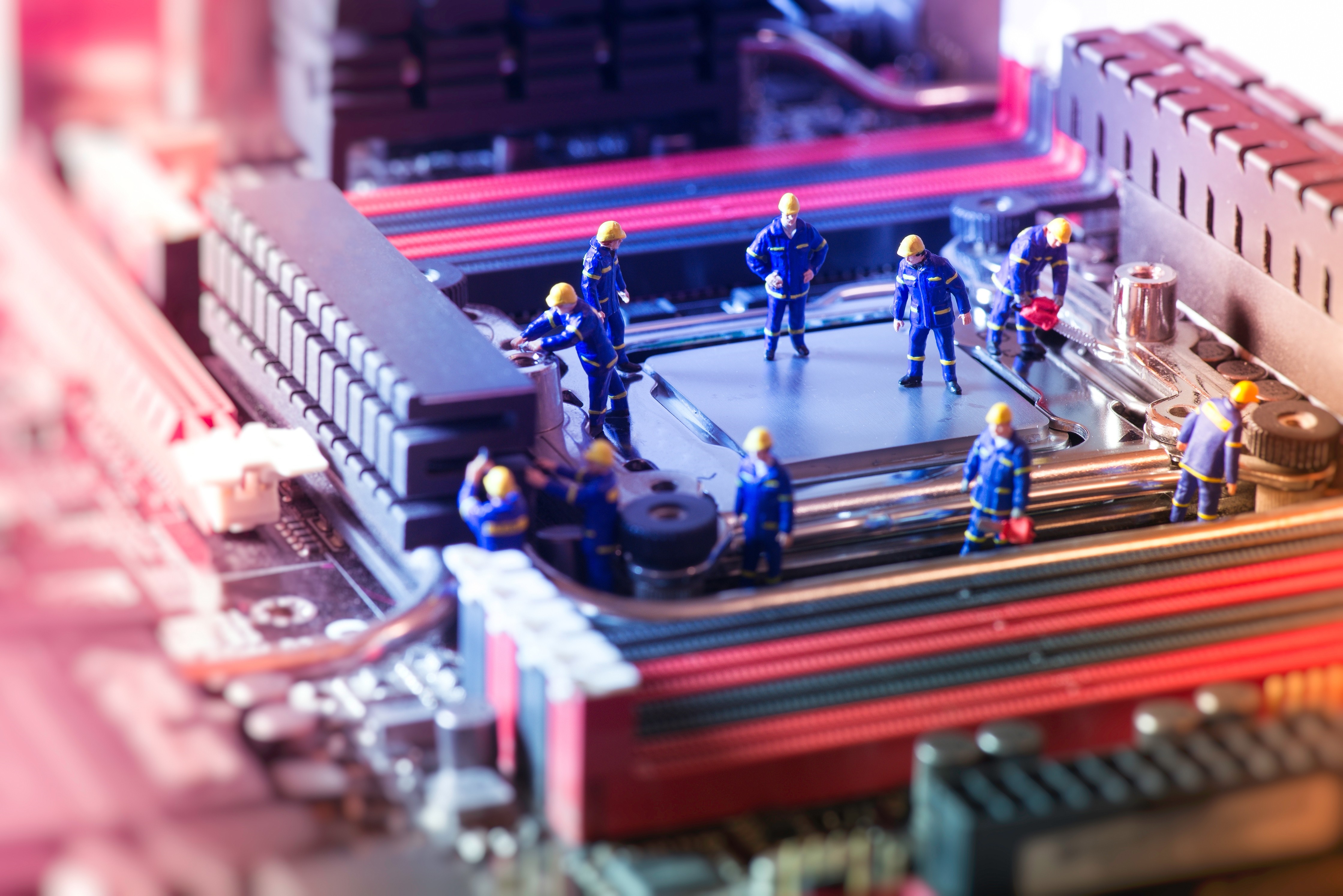 Miniature workers on a computer motherboard HD Wallpaper