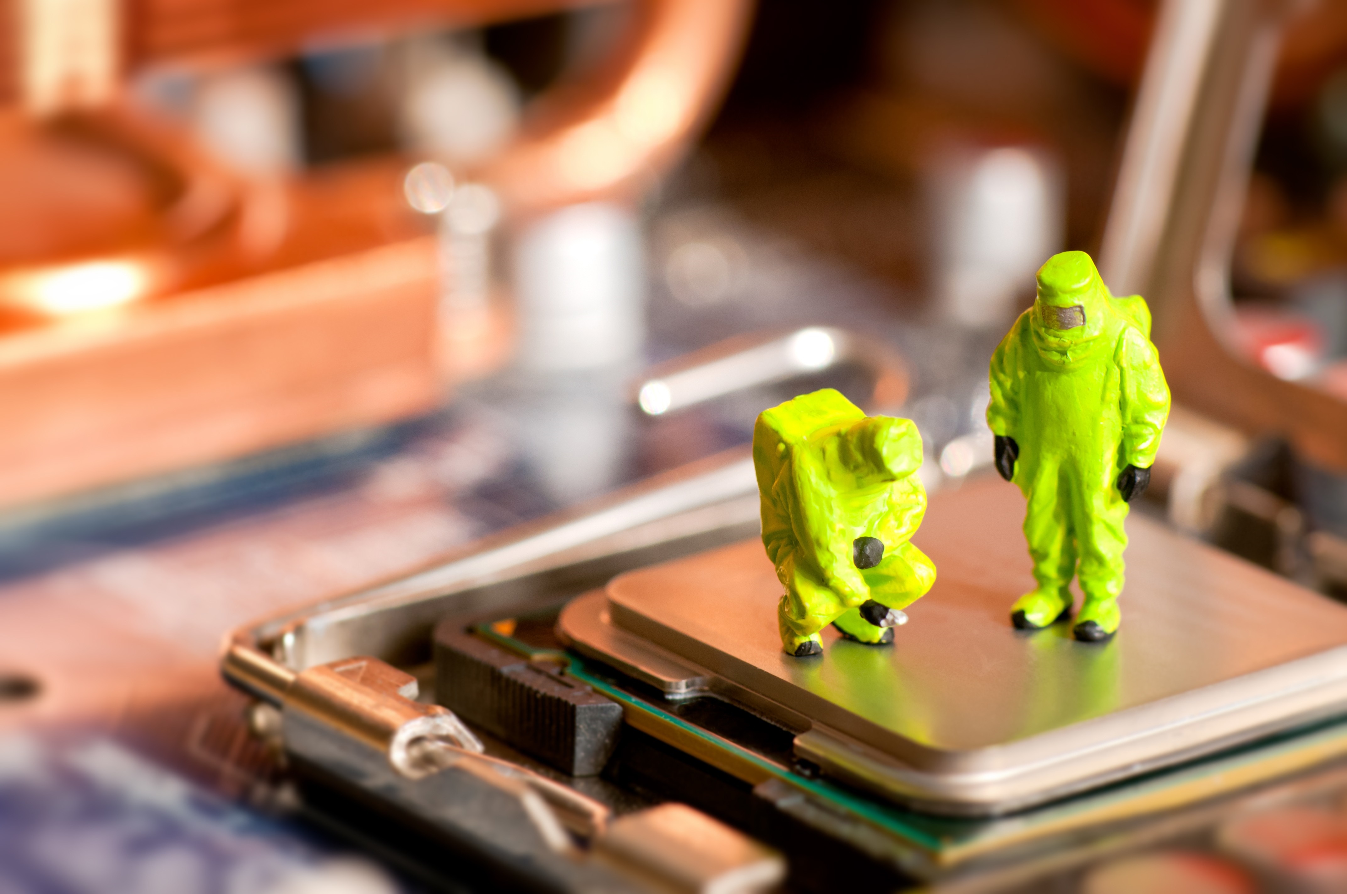 Miniature figures in hazmat suits on computer motherboard HD Wallpaper