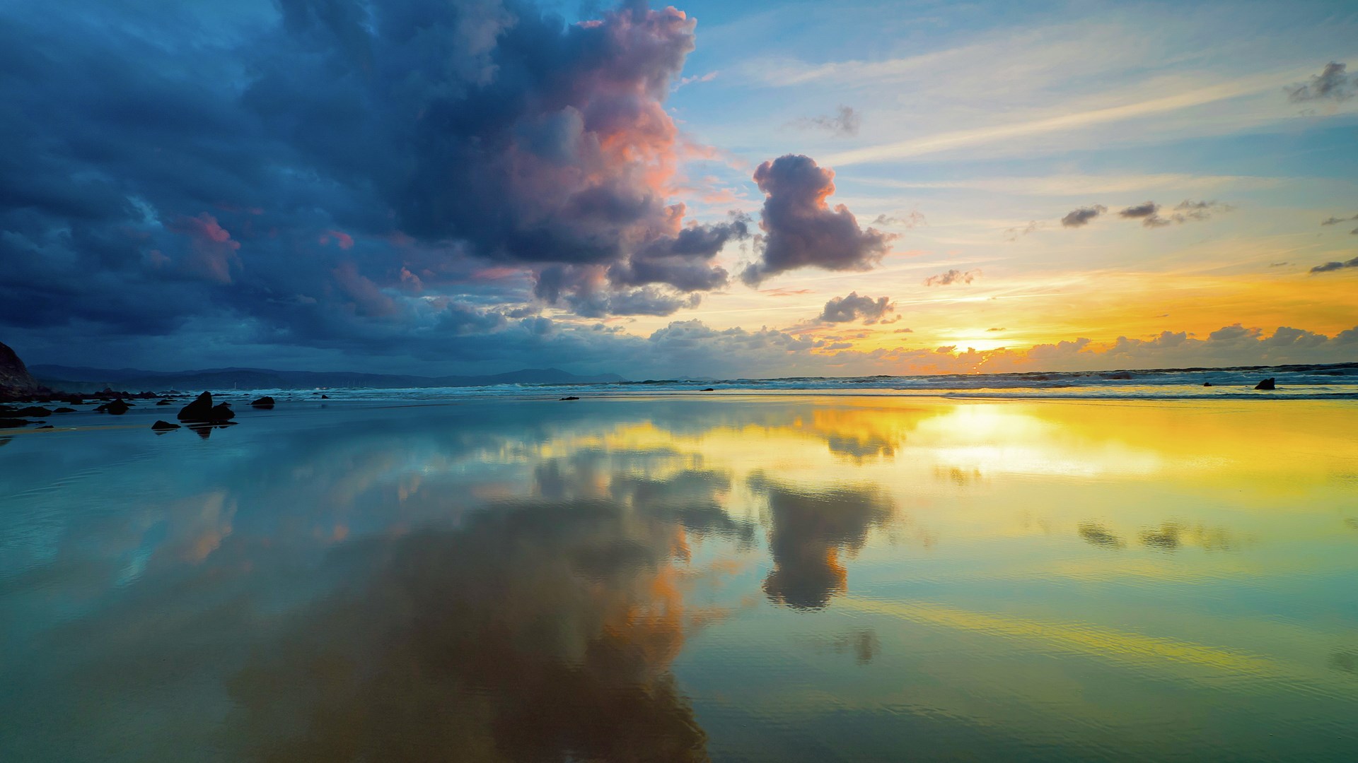 Sunset over a reflective beach with dramatic clouds HD Wallpaper