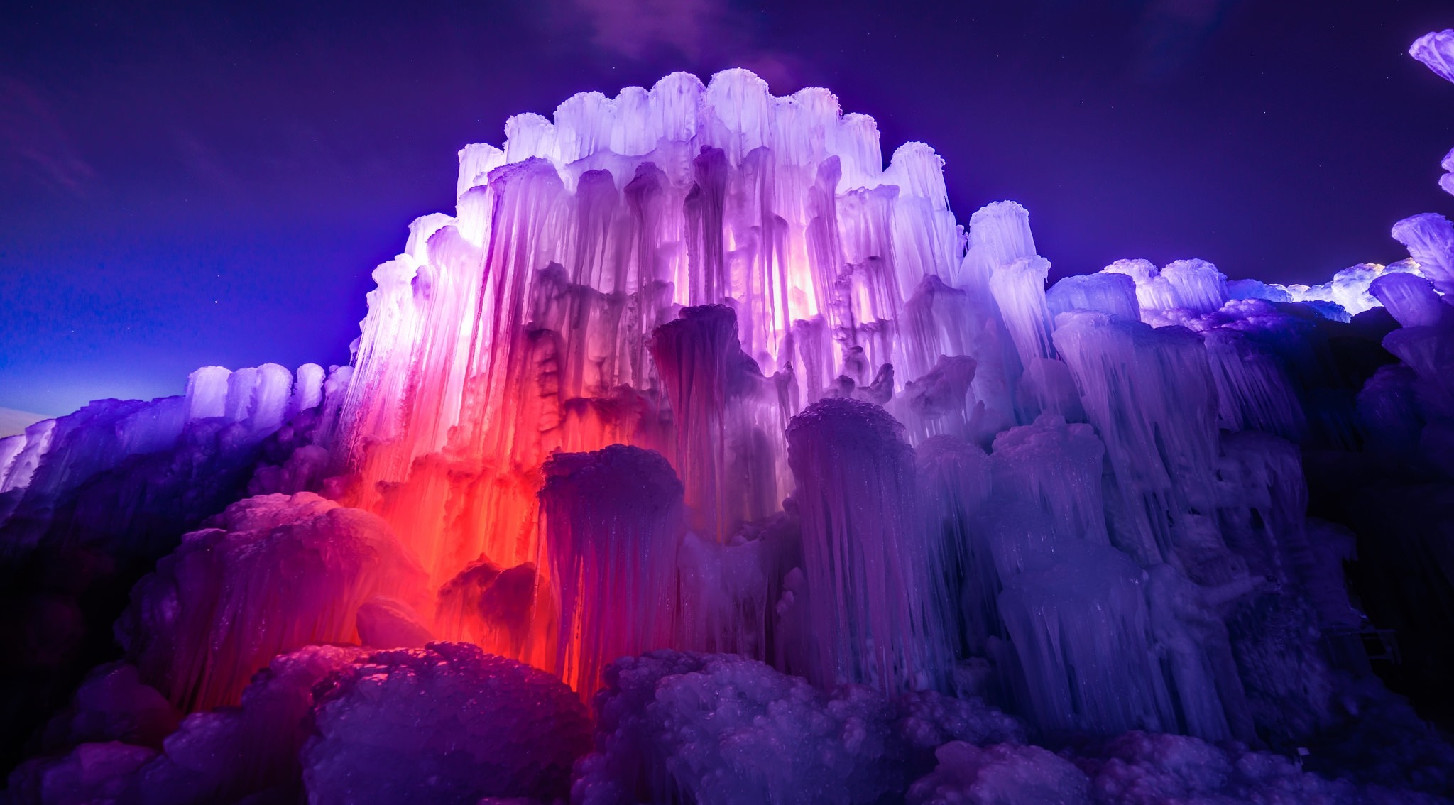 Ice castle illuminated with colorful lights at night HD Wallpaper