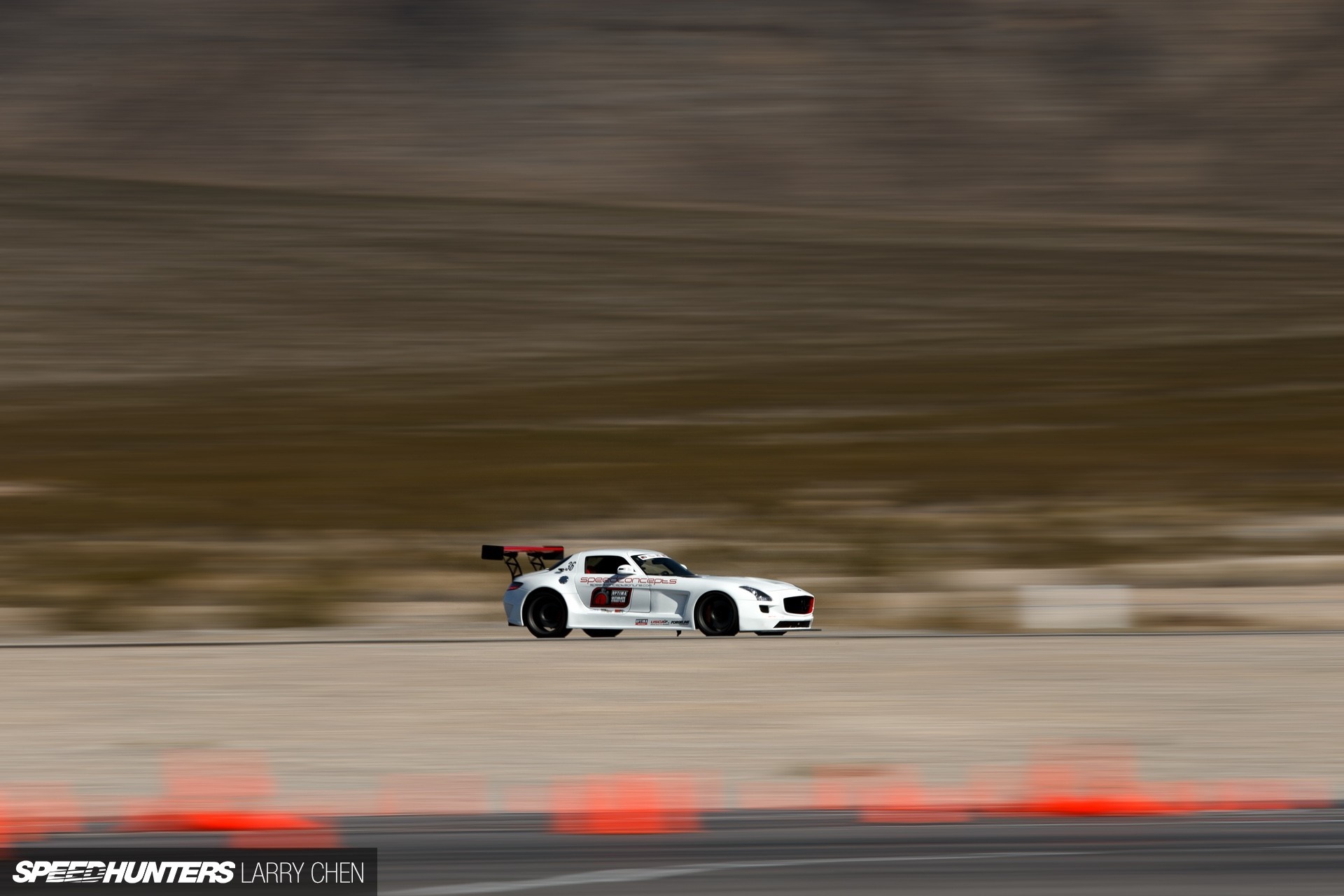 White Mercedes-Benz SLS AMG racing on a track HD Wallpaper