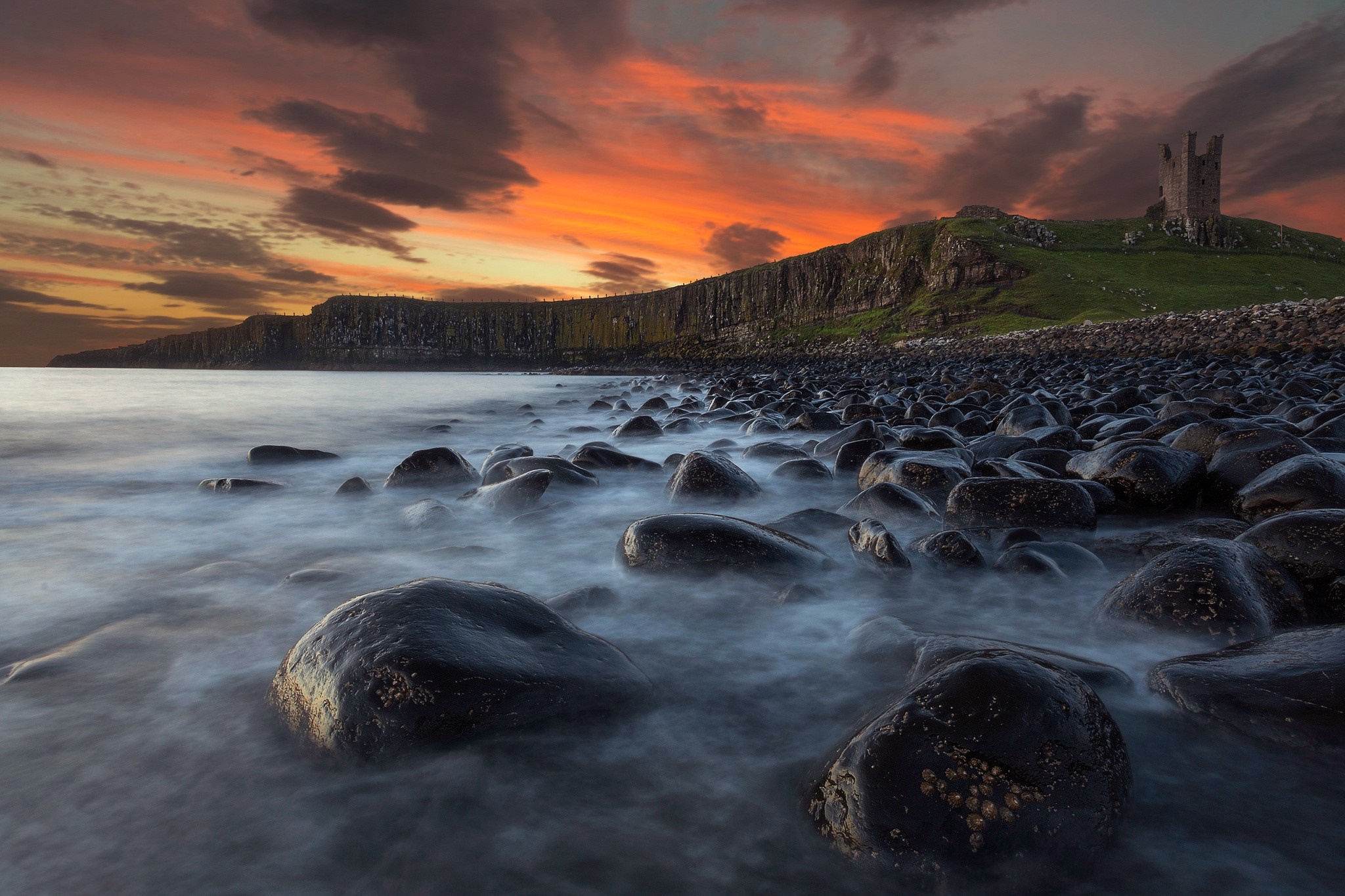 Castle on a cliff overlooking a rocky shore at sunset HD Wallpaper