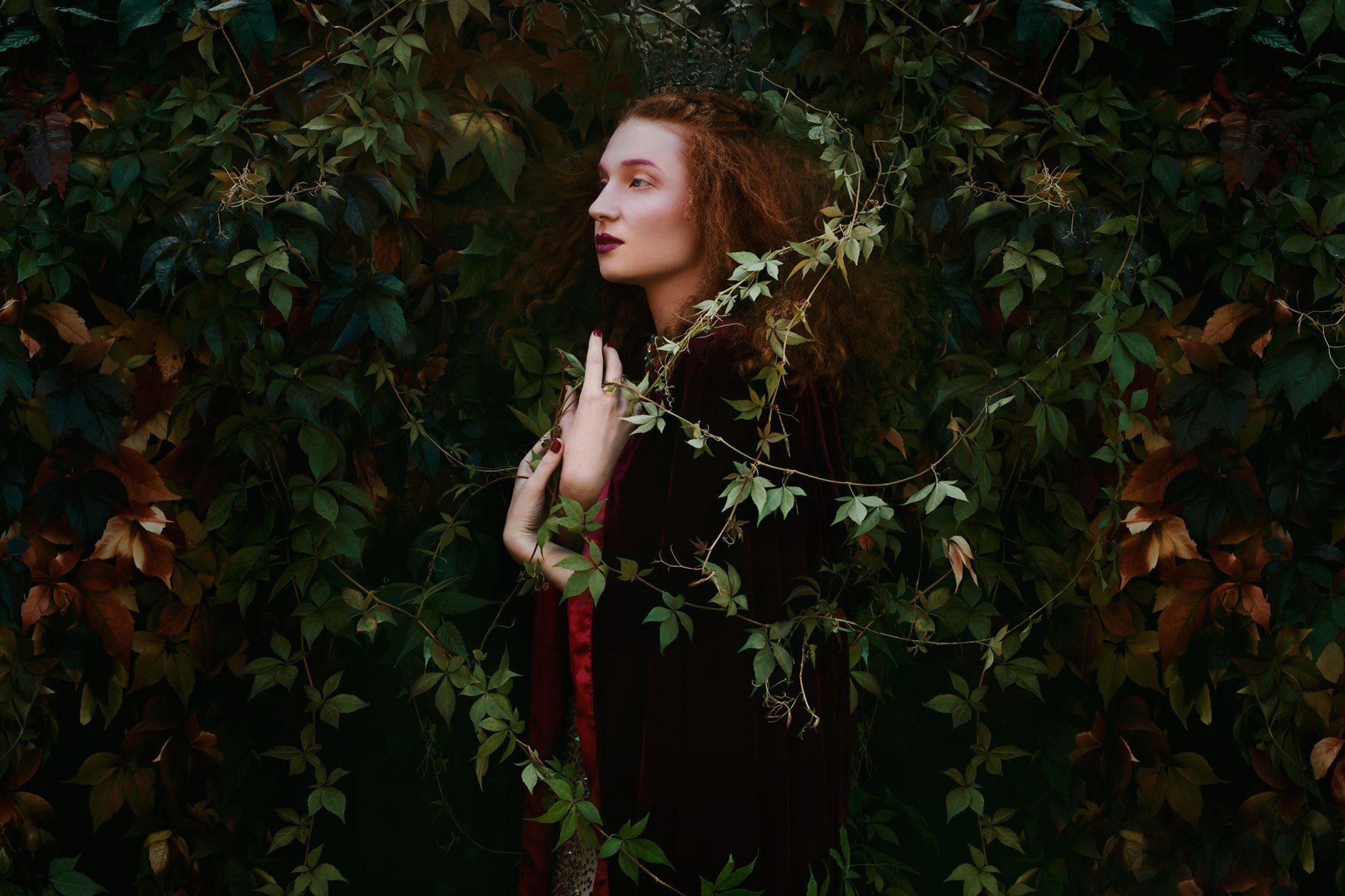 Woman with red hair in a dark dress surrounded by foliage HD Wallpaper