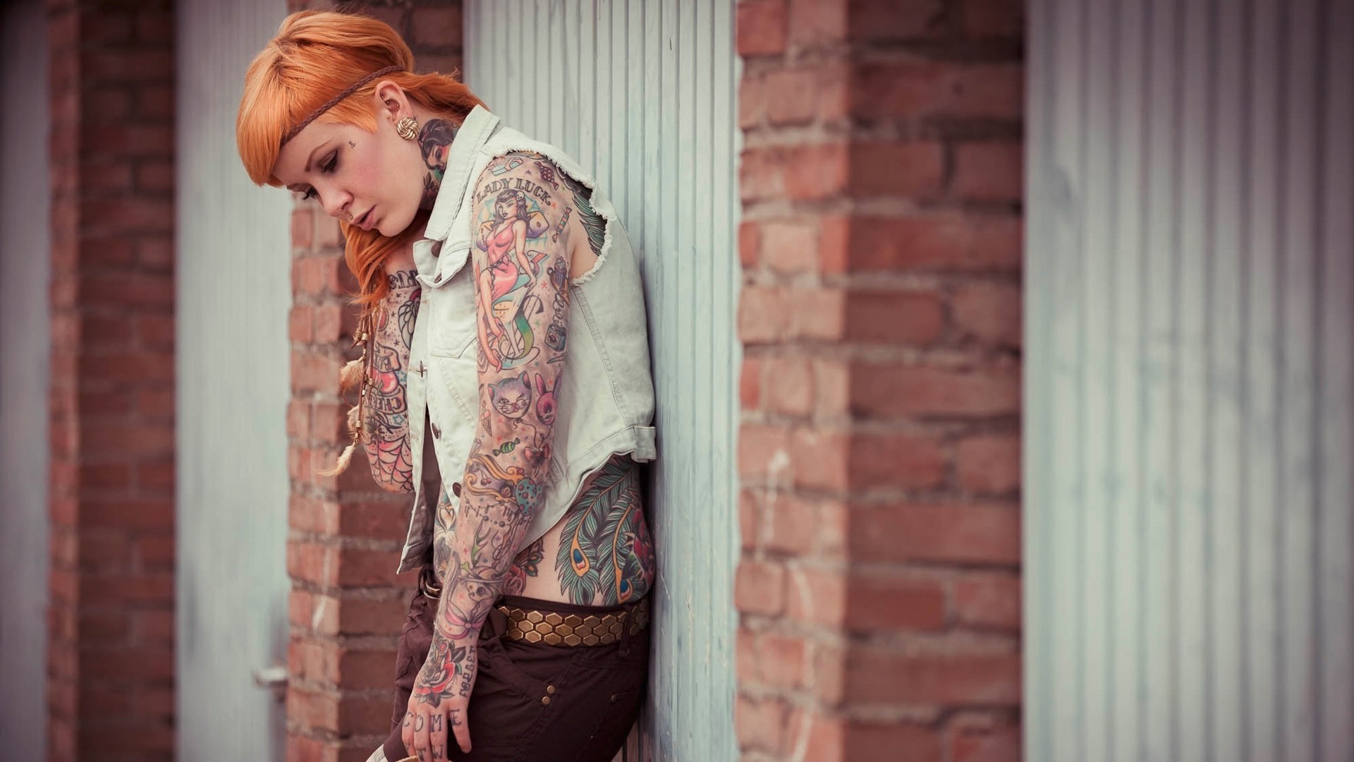 Woman with extensive tattoos leaning against a wall HD Wallpaper