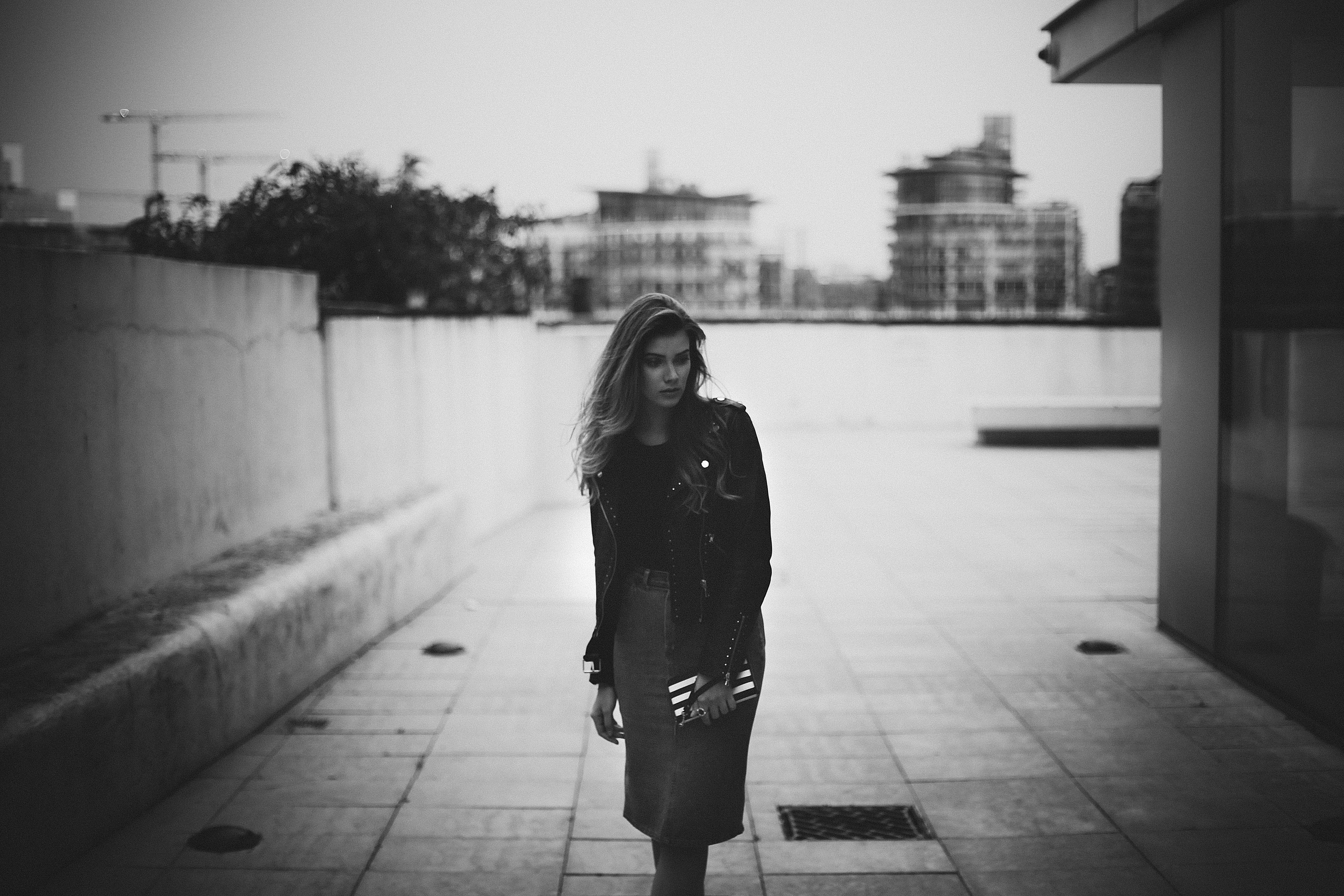 Woman in black jacket and skirt holding a clutch HD Wallpaper
