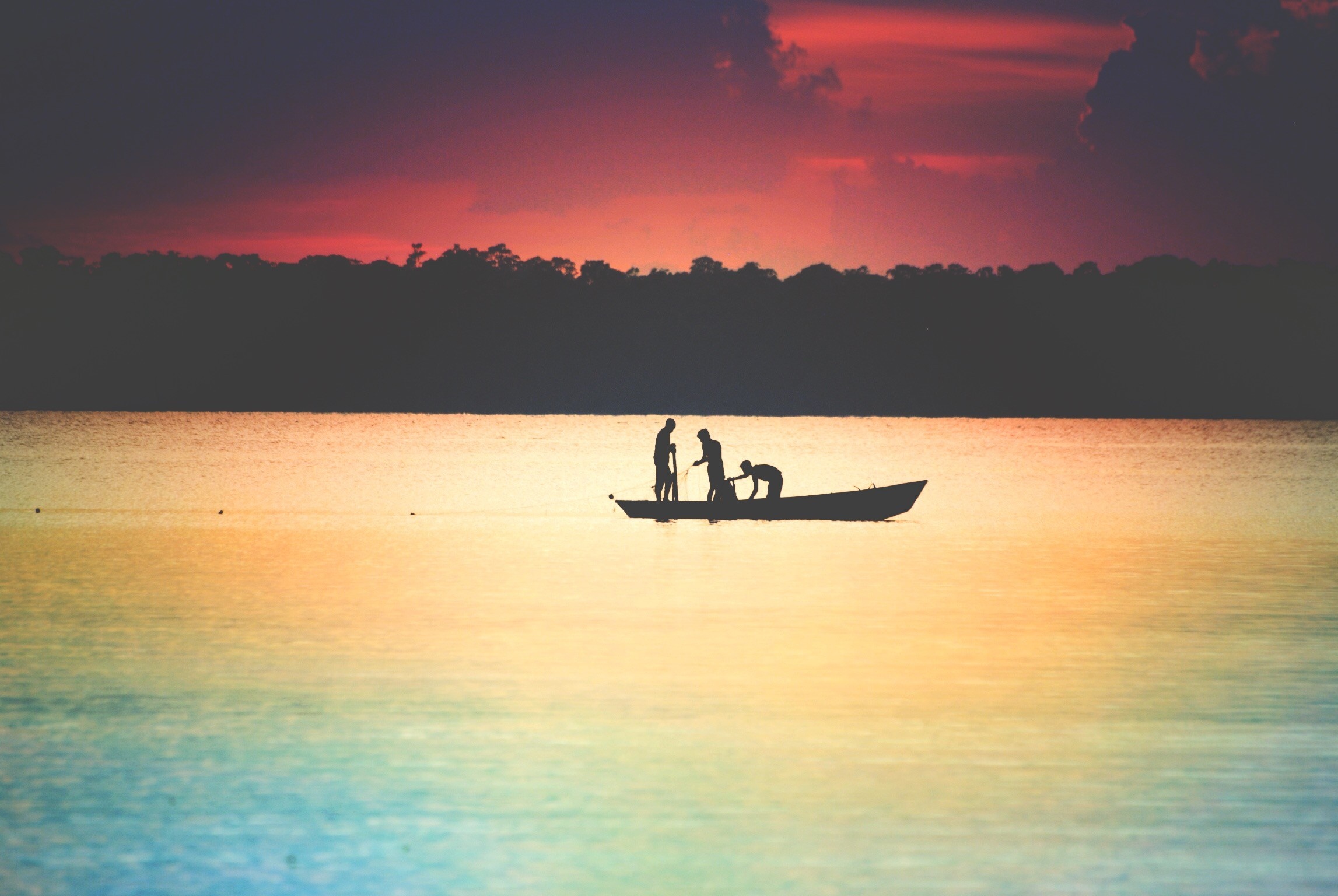 Silhouettes of people in a boat at sunset over the ocean HD Wallpaper