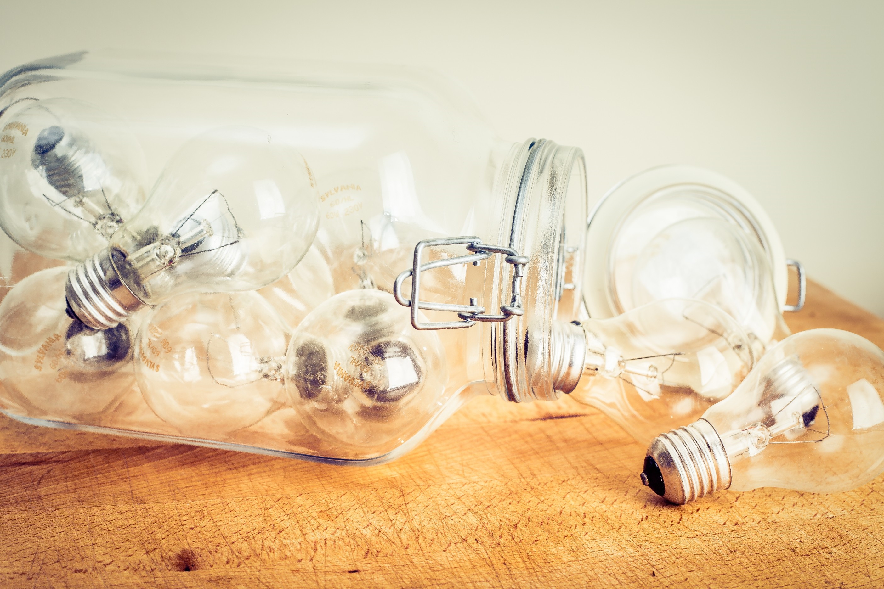 Lightbulbs in a glass jar on a wooden surface HD Wallpaper