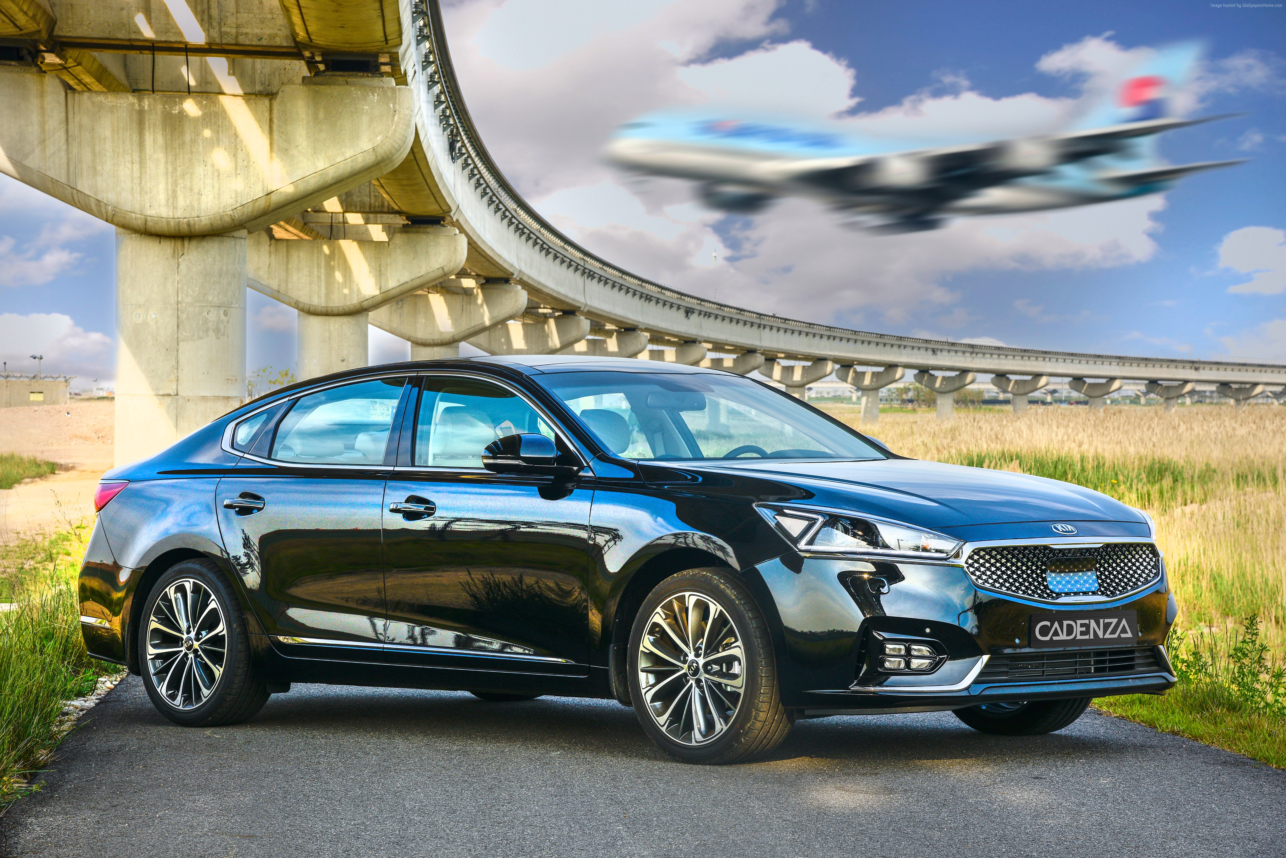 Black Kia Cadenza sedan under elevated tracks with airplane HD Wallpaper