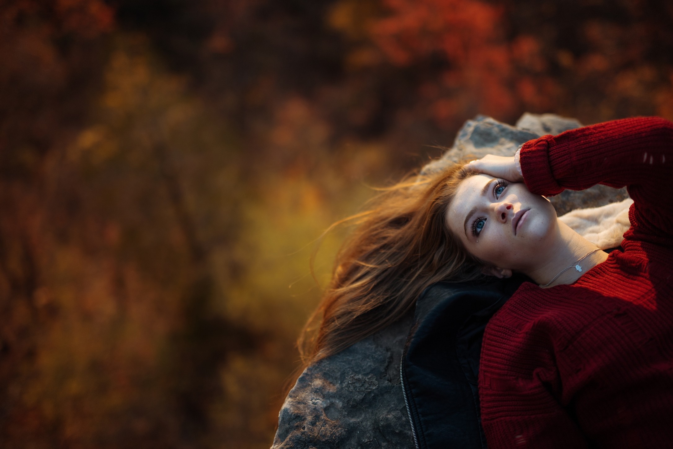 Woman in red sweater lying on rocks with autumn background HD Wallpaper