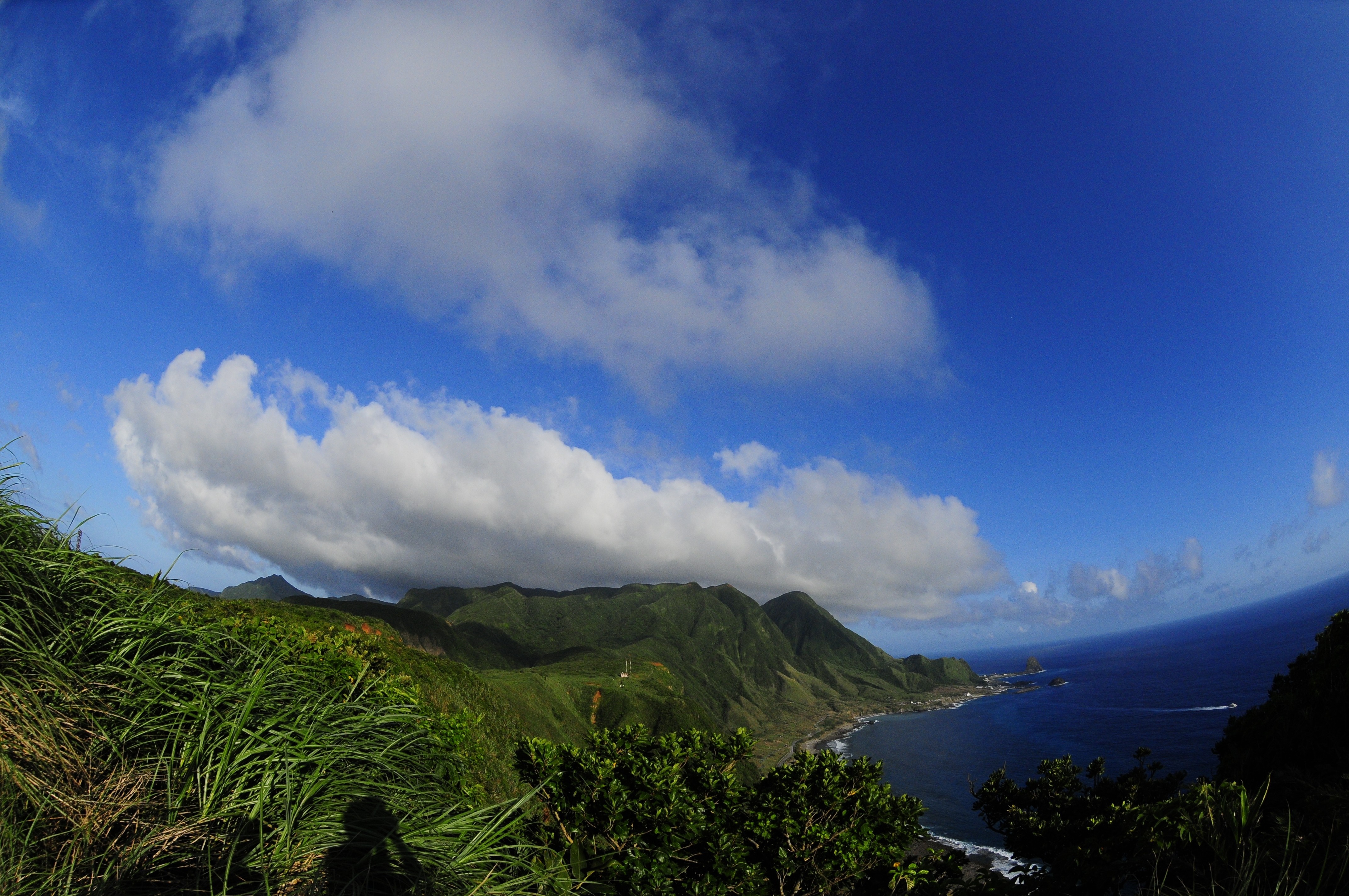 Green mountains and sea under a cloudy blue sky HD Wallpaper