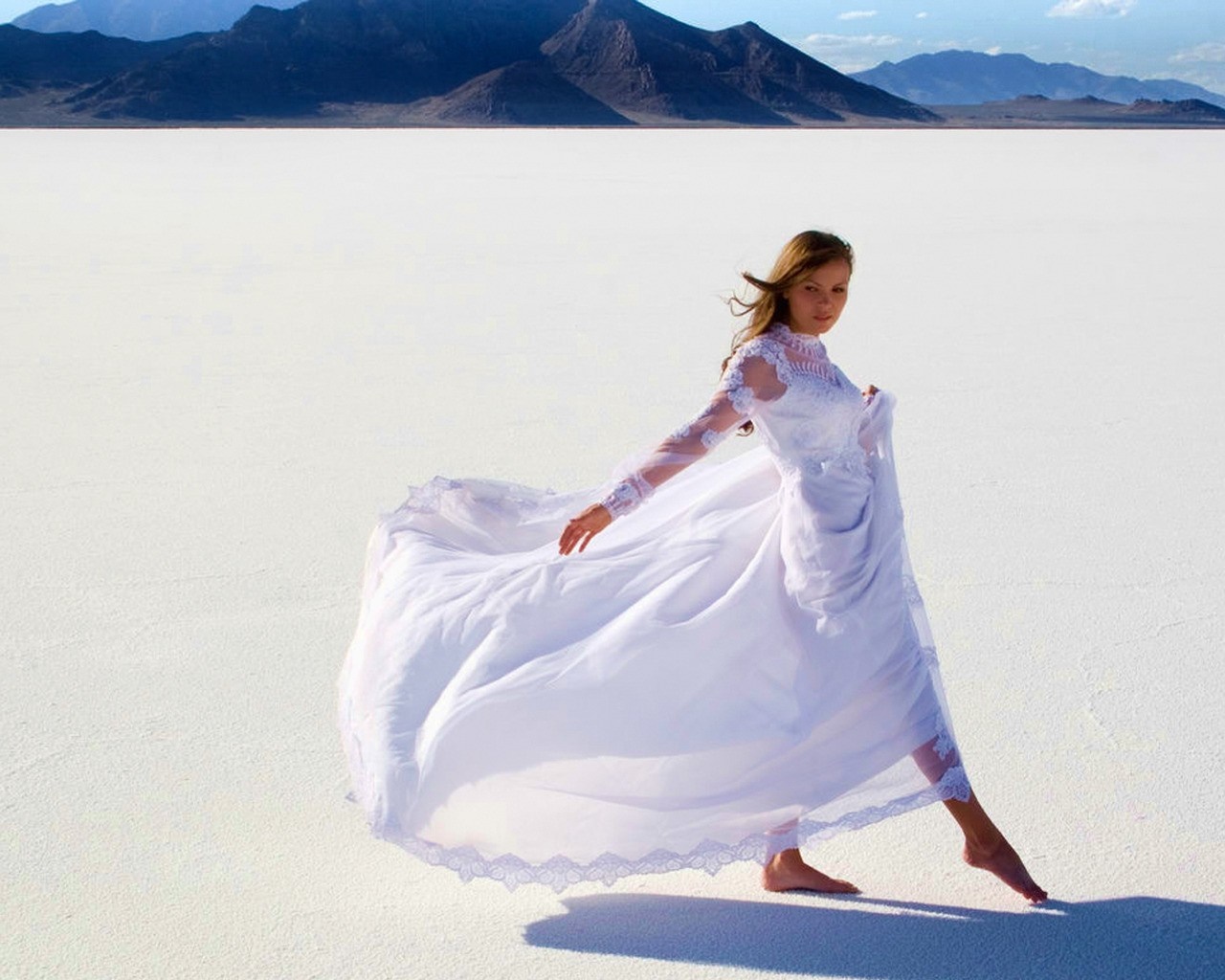 Woman in white dress on salt flats with mountains HD Wallpaper