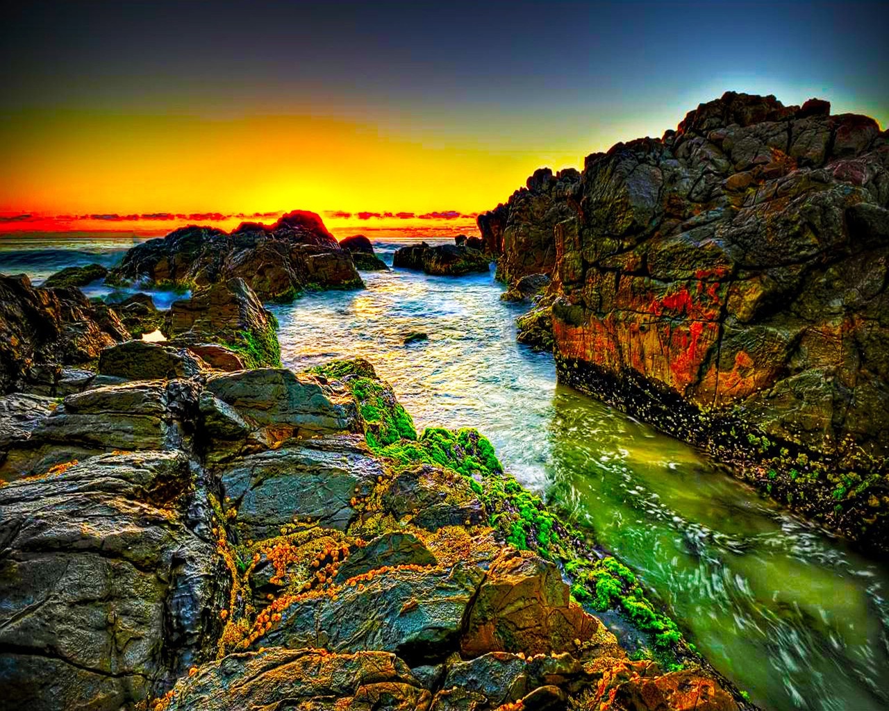 Rocky coast at sunset with vibrant sky and ocean HD Wallpaper