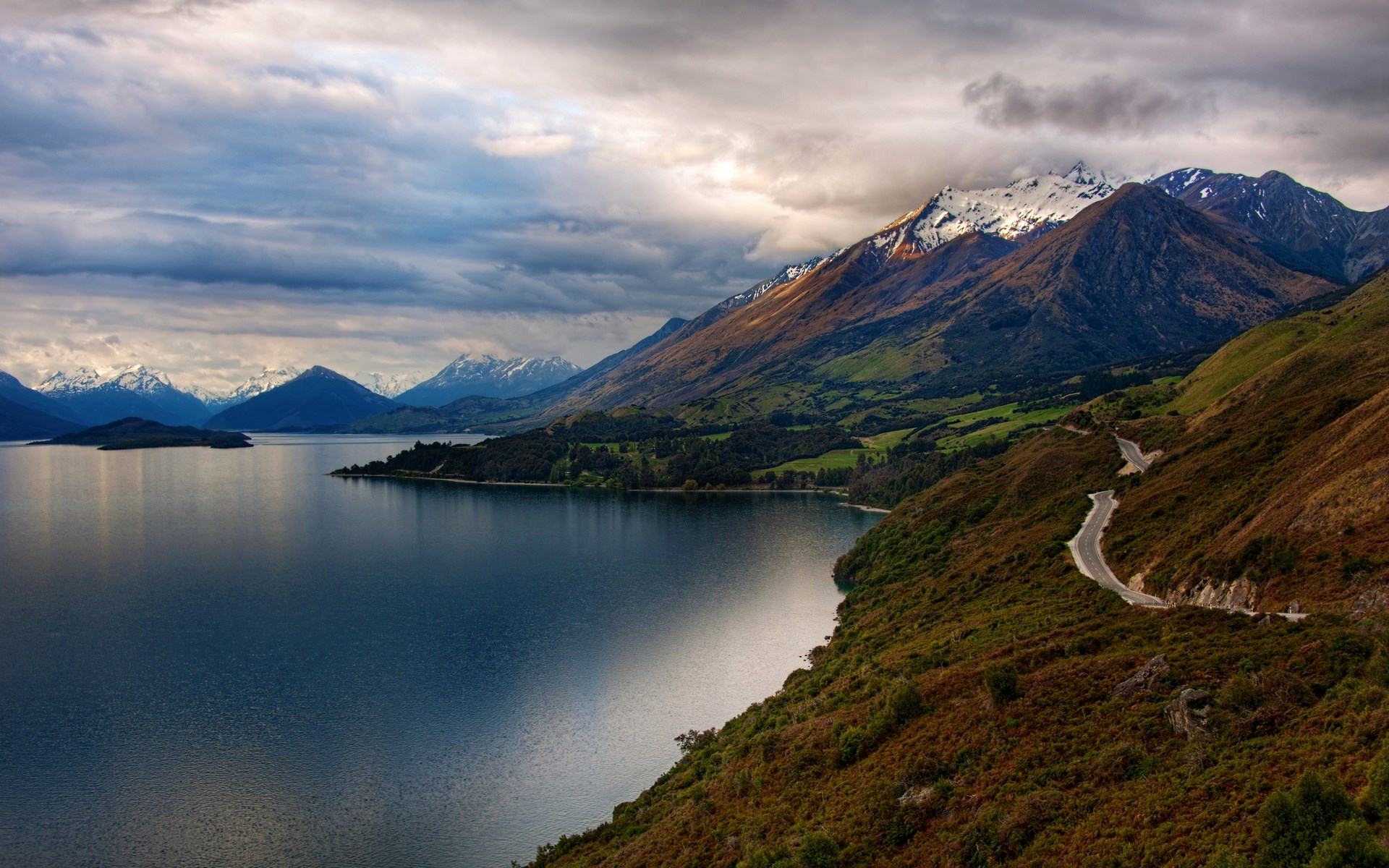 Winding road along a lake and mountains HD Wallpaper