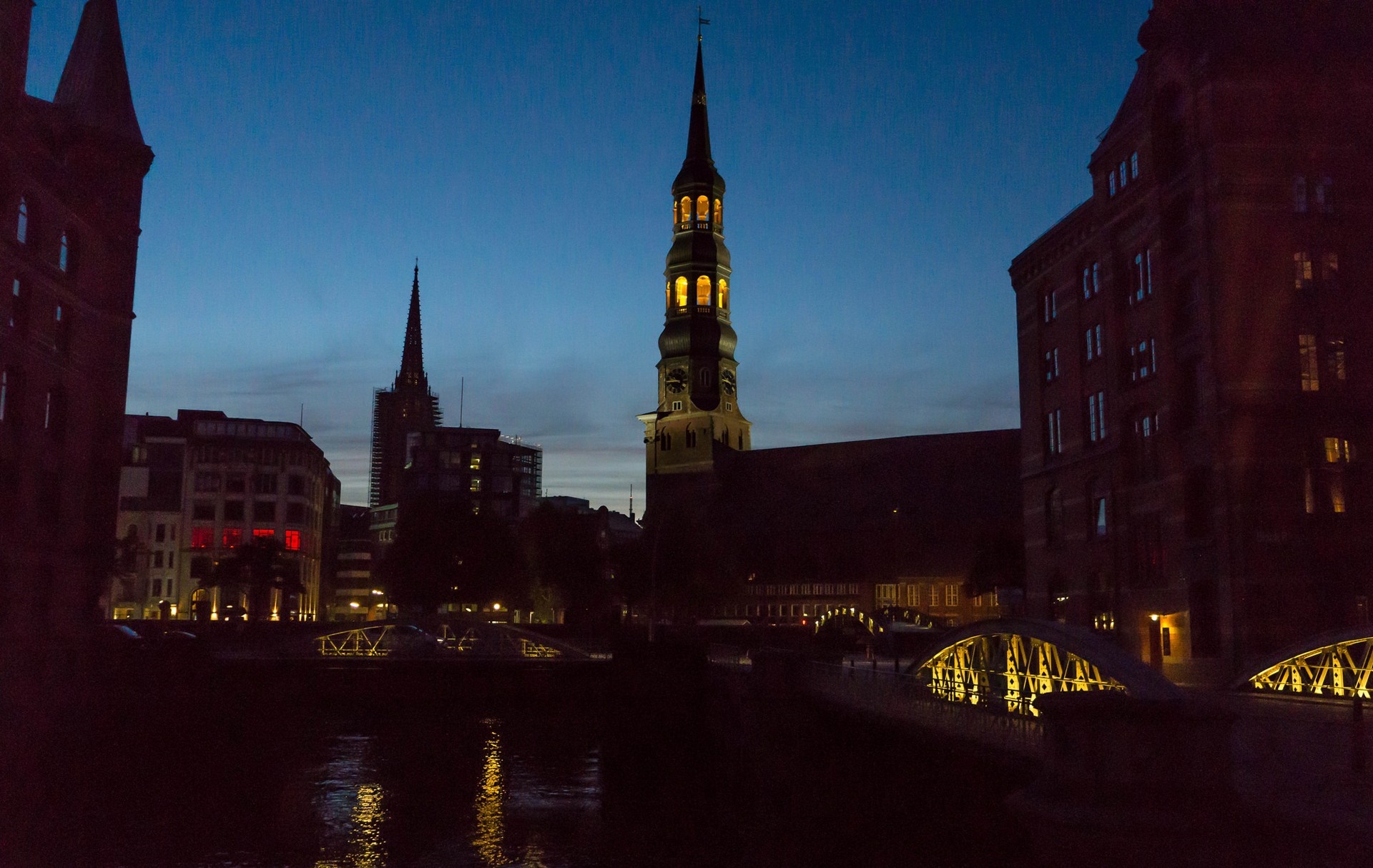 Cityscape at dusk with illuminated towers and bridges over water HD Wallpaper