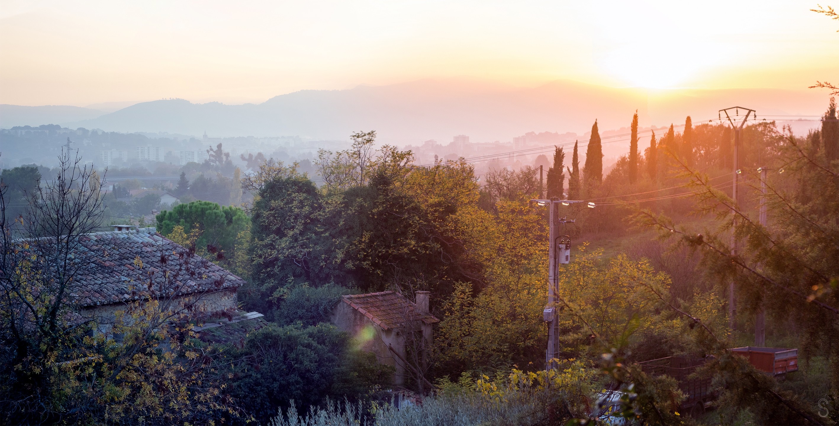 Sunset over a misty valley with houses and trees HD Wallpaper
