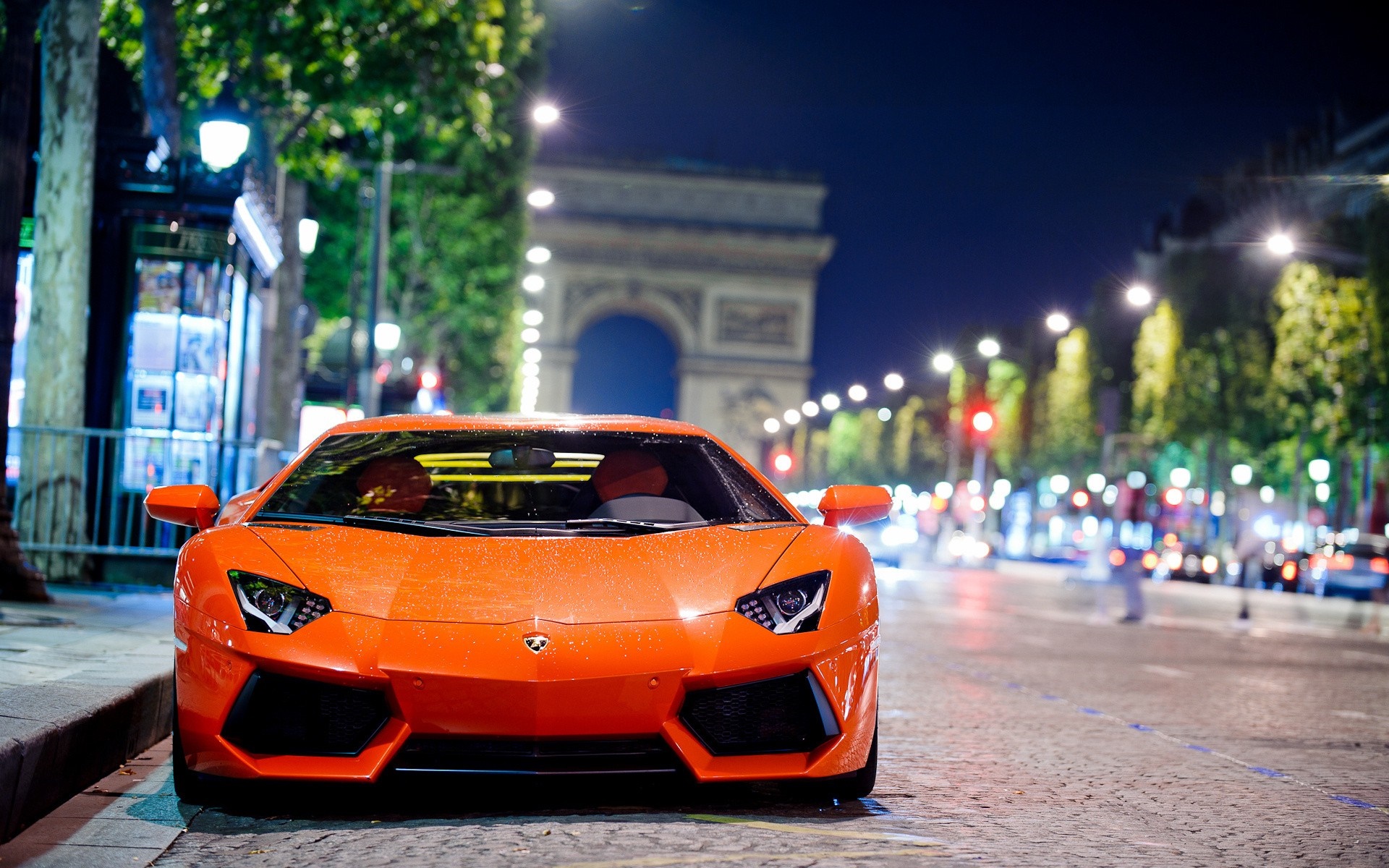 Orange Lamborghini Aventador parked near Arc de Triomphe at night HD Wallpaper