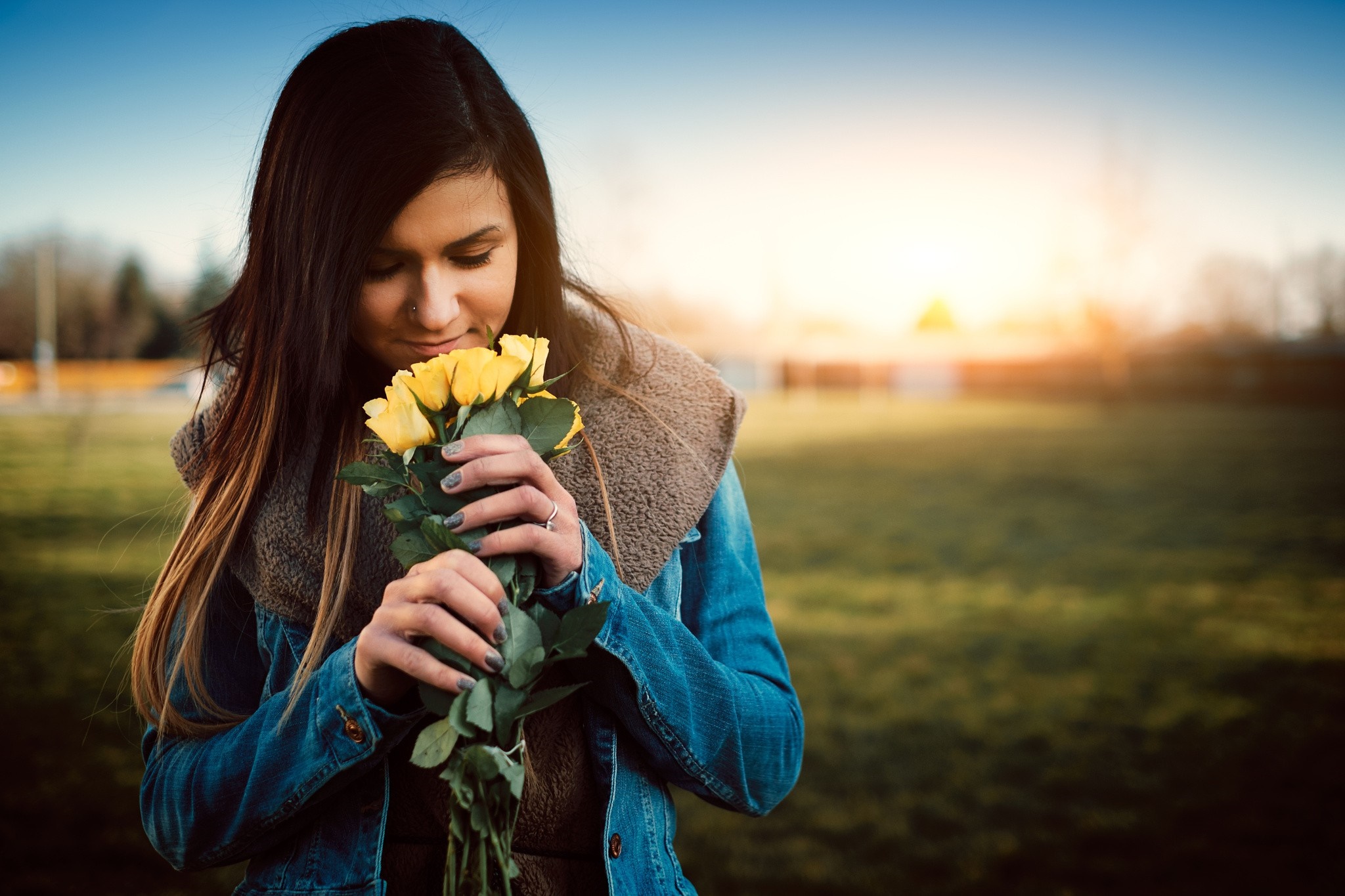 Woman smelling yellow roses outdoors at sunset HD Wallpaper