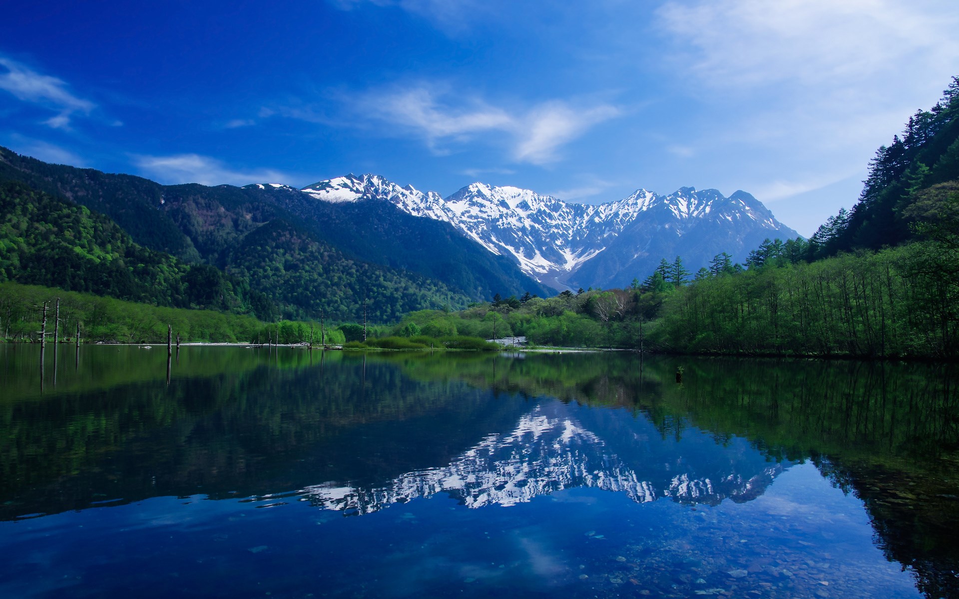 Snow-capped mountains reflected in a calm lake HD Wallpaper
