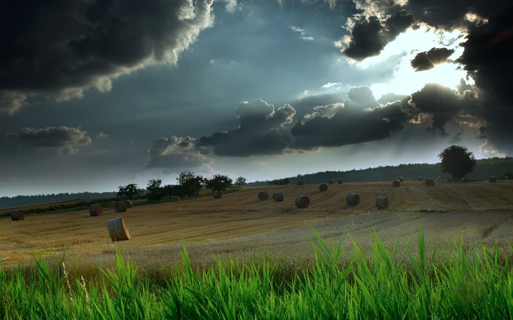Hay bales in a field under dramatic clouds HD Wallpaper