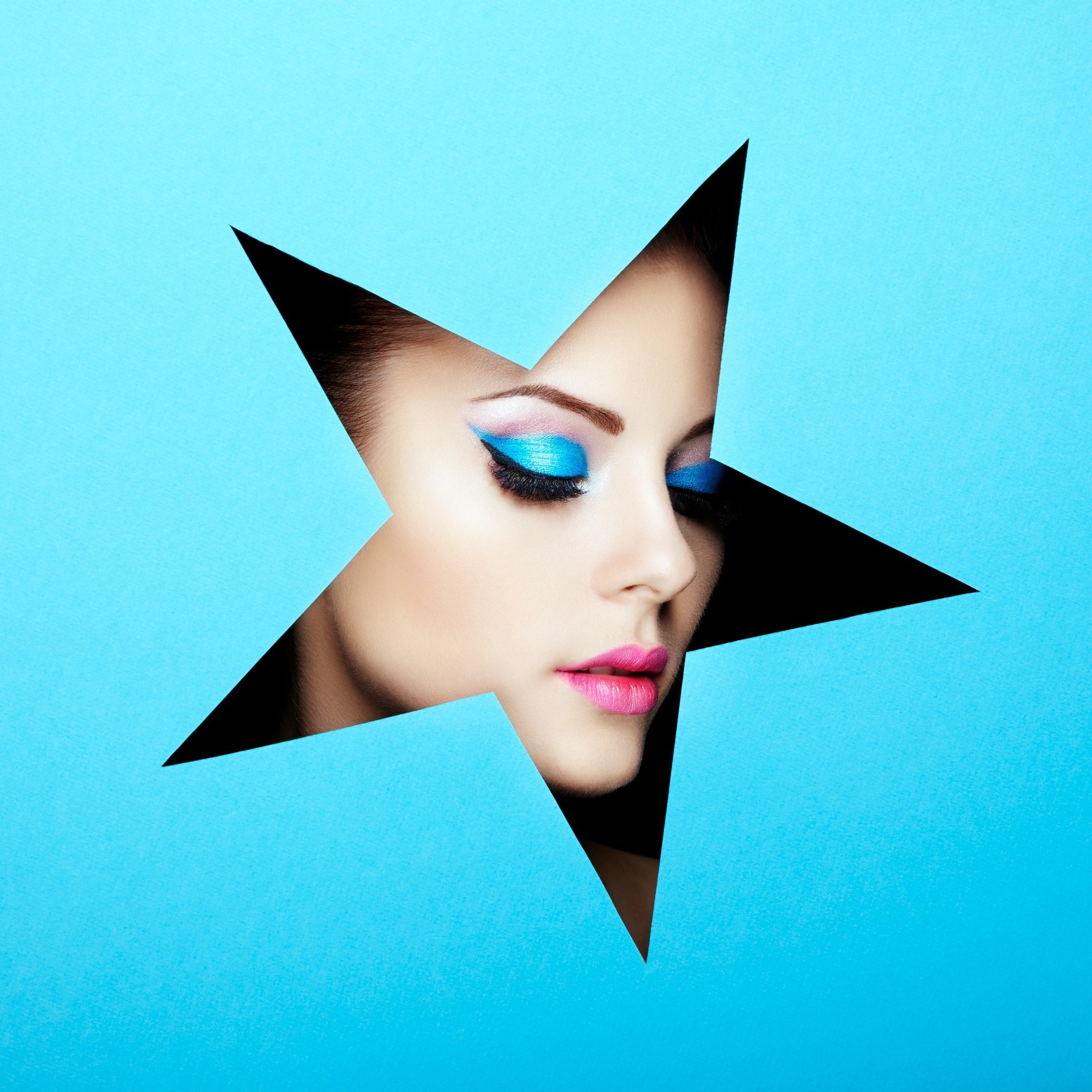 Woman with blue eye makeup peeking through a star cutout HD Wallpaper