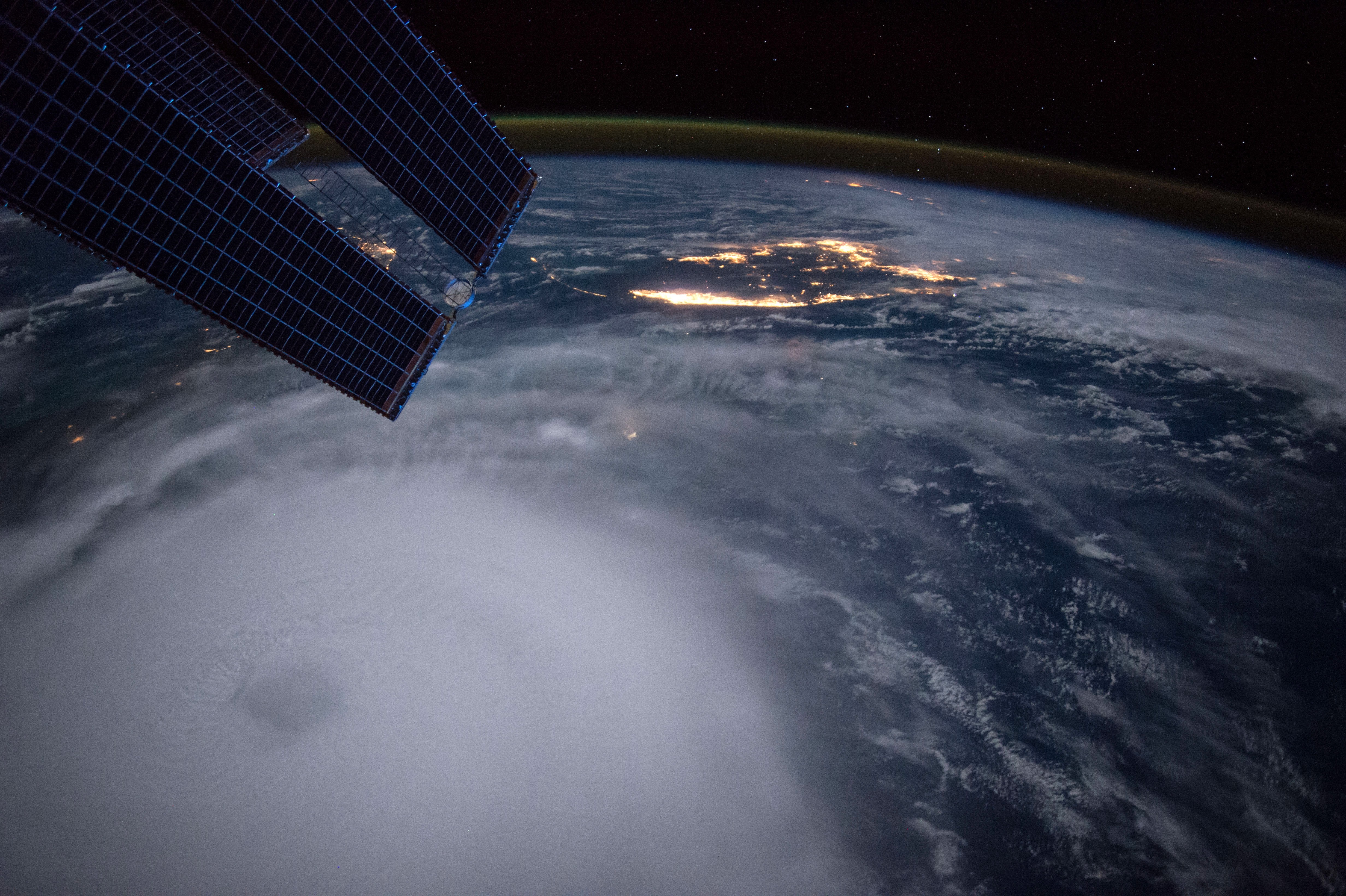 Earth from space with hurricane and ISS solar panels HD Wallpaper