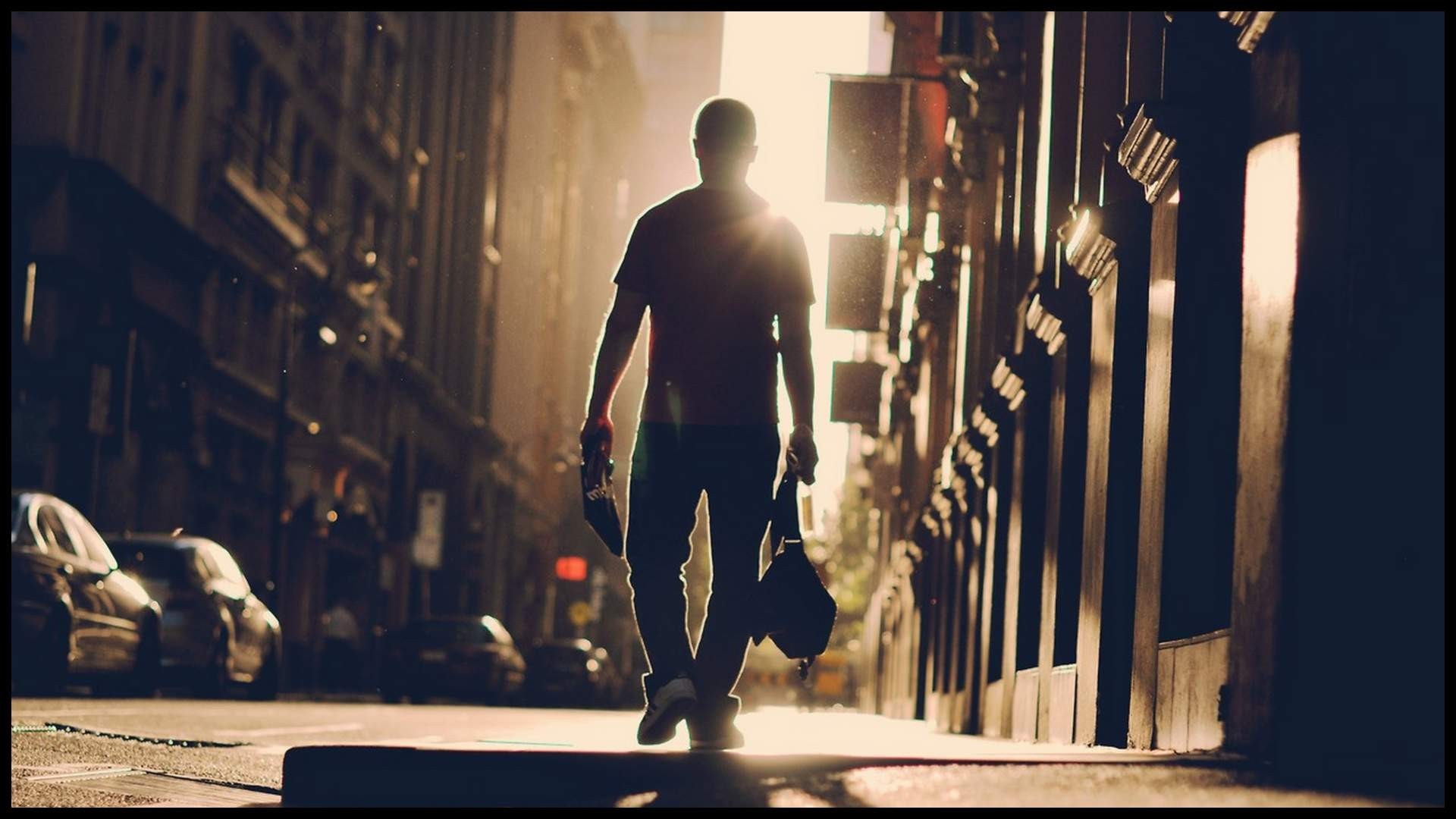 Man walking down a city street at sunset HD Wallpaper