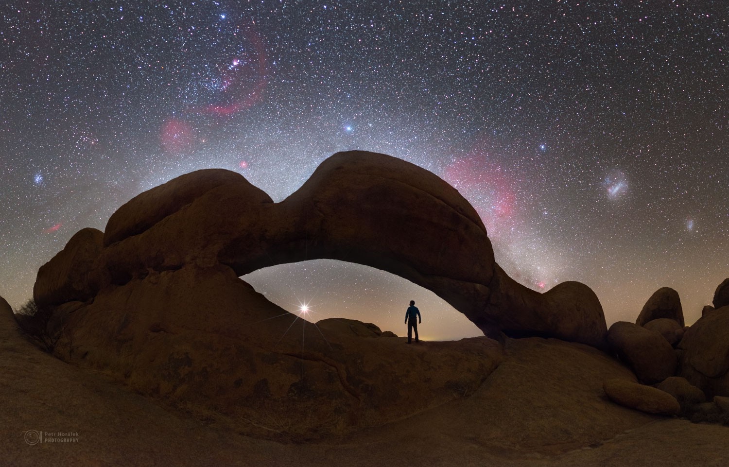 Silhouette under rock arch with starry sky HD Wallpaper