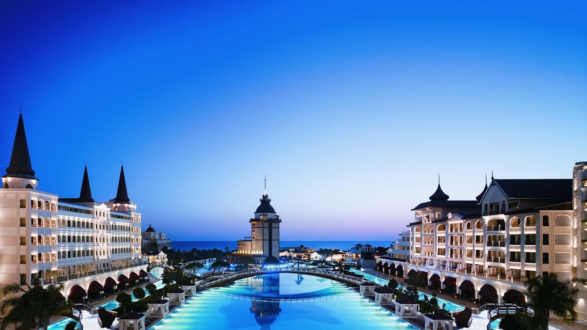Luxury resort with waterways and illuminated buildings at dusk HD Wallpaper
