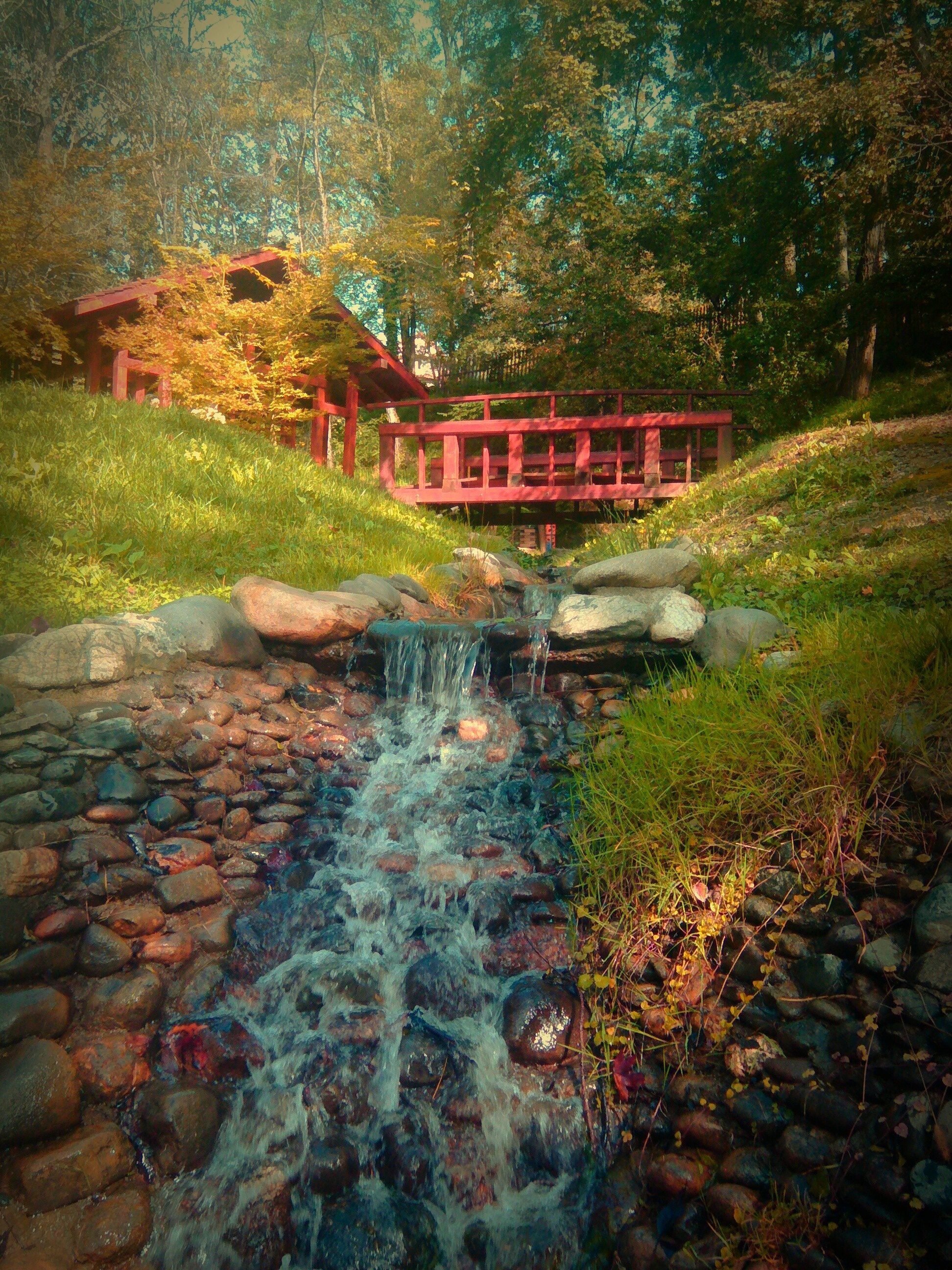 Red bridge over a stream with a small cabin HD Wallpaper