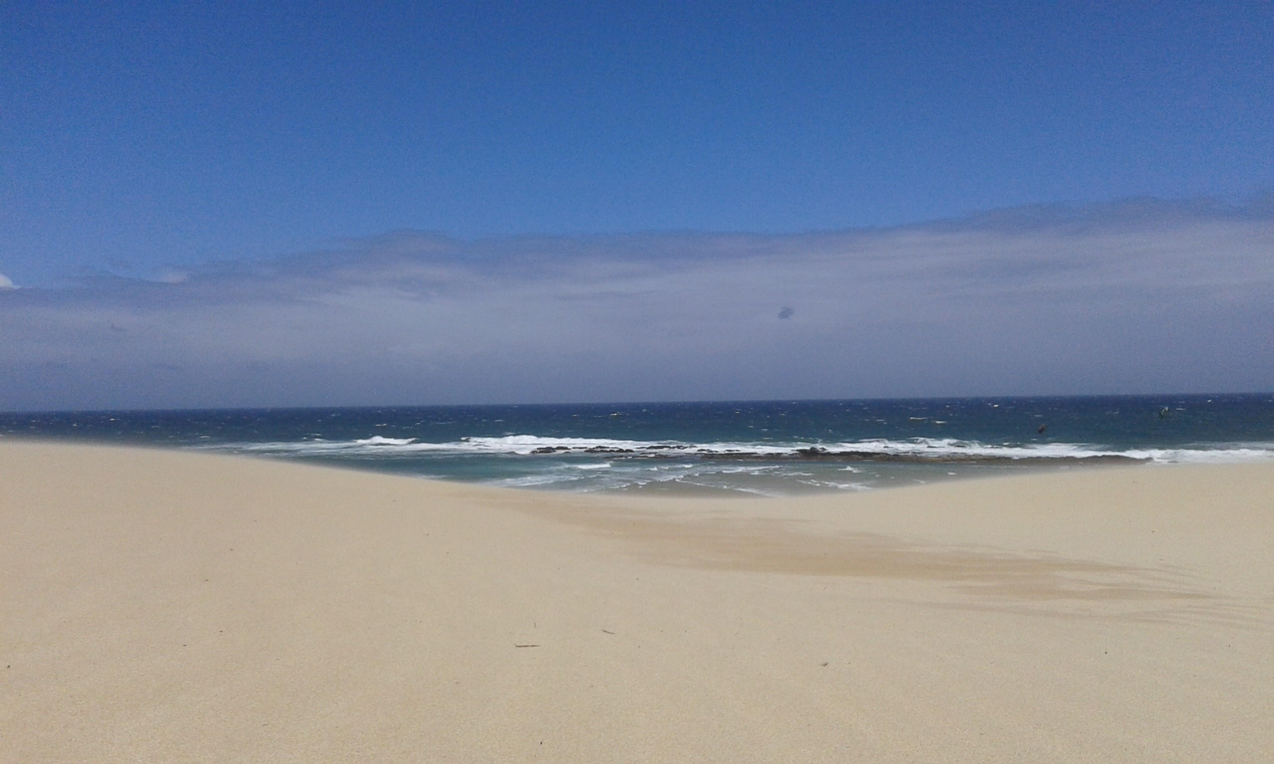Sandy beach with ocean waves and blue sky HD Wallpaper