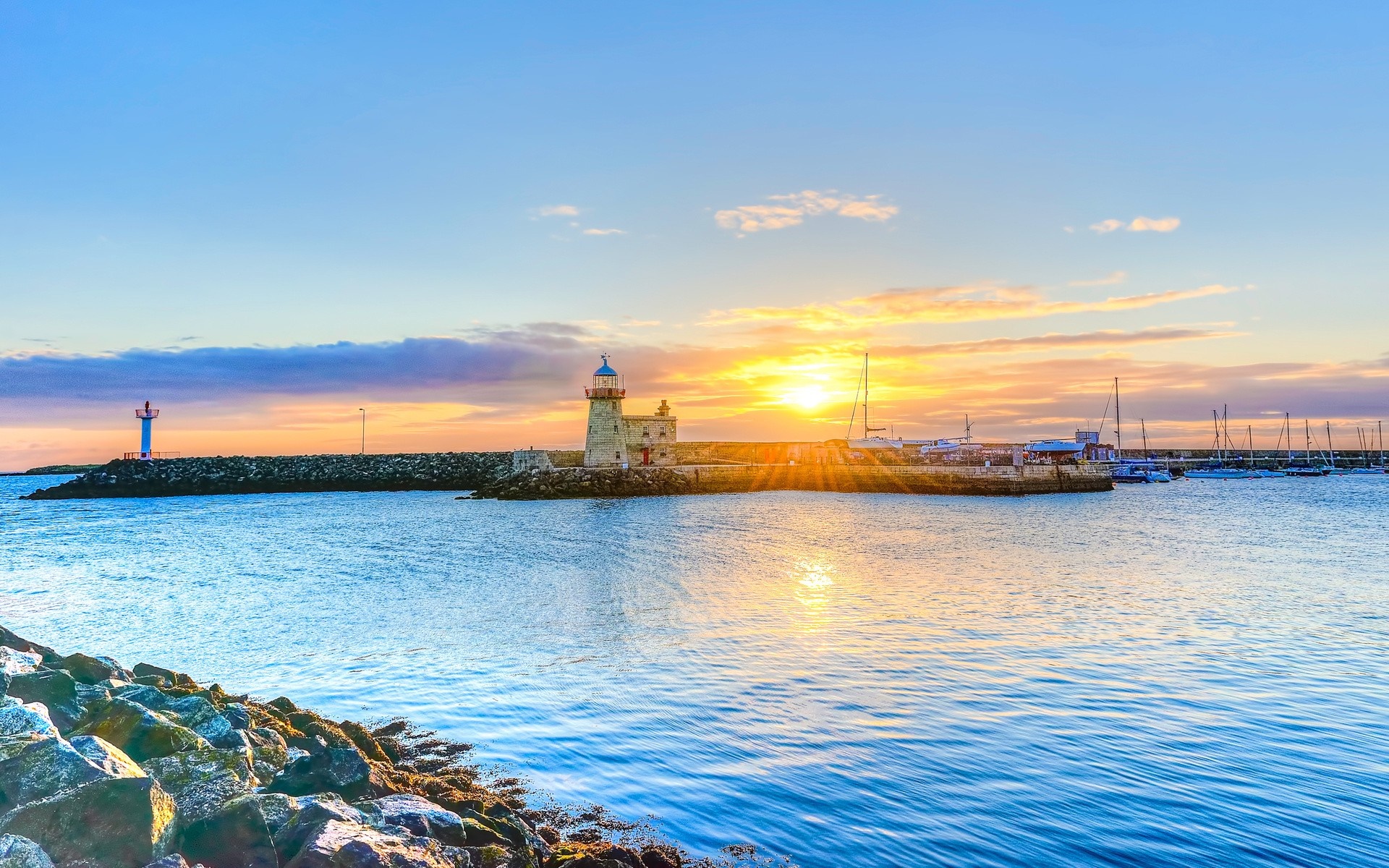Sunset over a harbor with lighthouses and sailboats HD Wallpaper