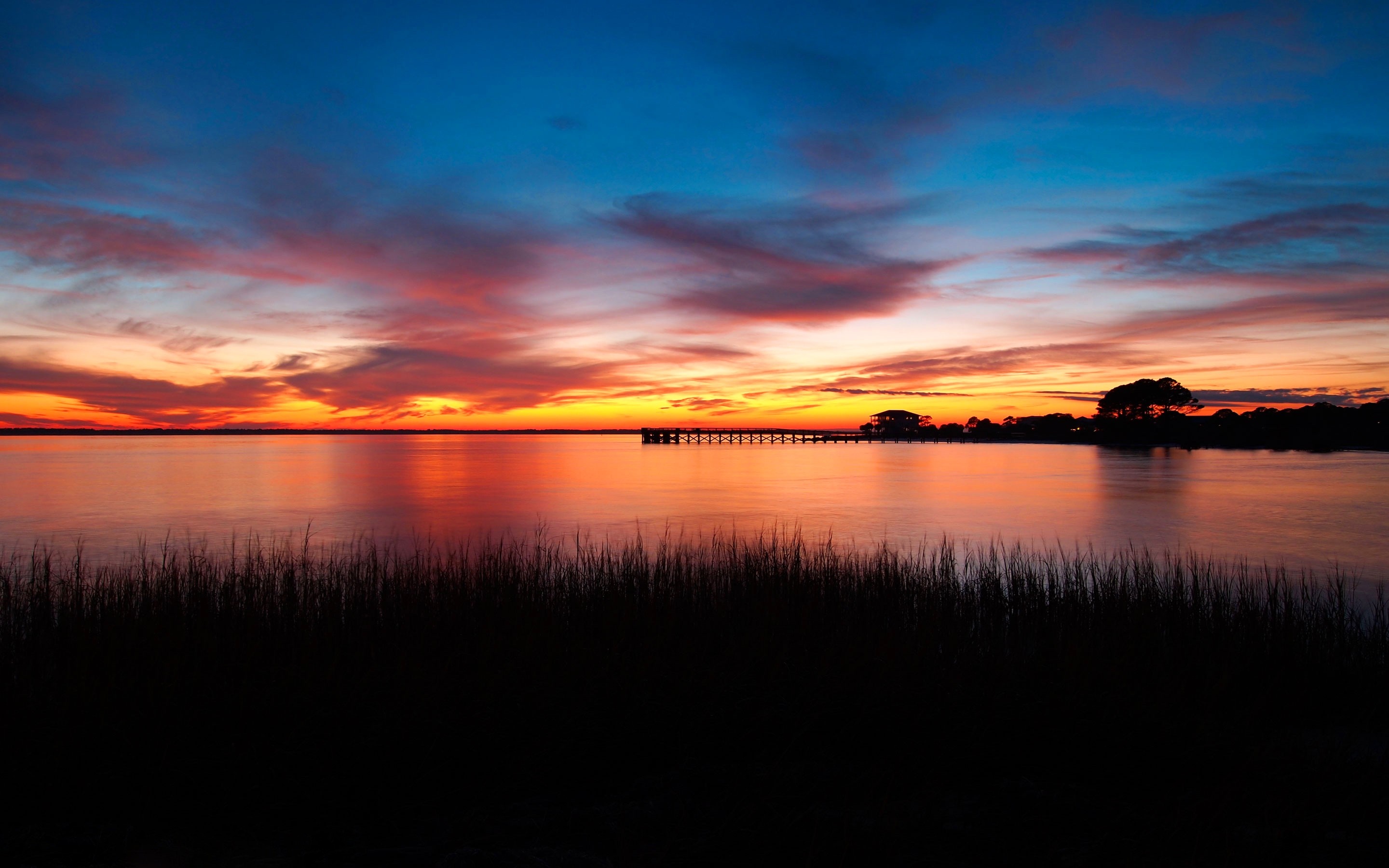 Sunset over a calm body of water with a pier HD Wallpaper