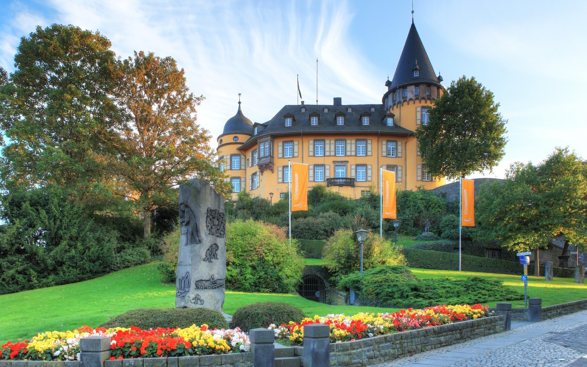 Yellow castle with a conical tower and flower garden HD Wallpaper