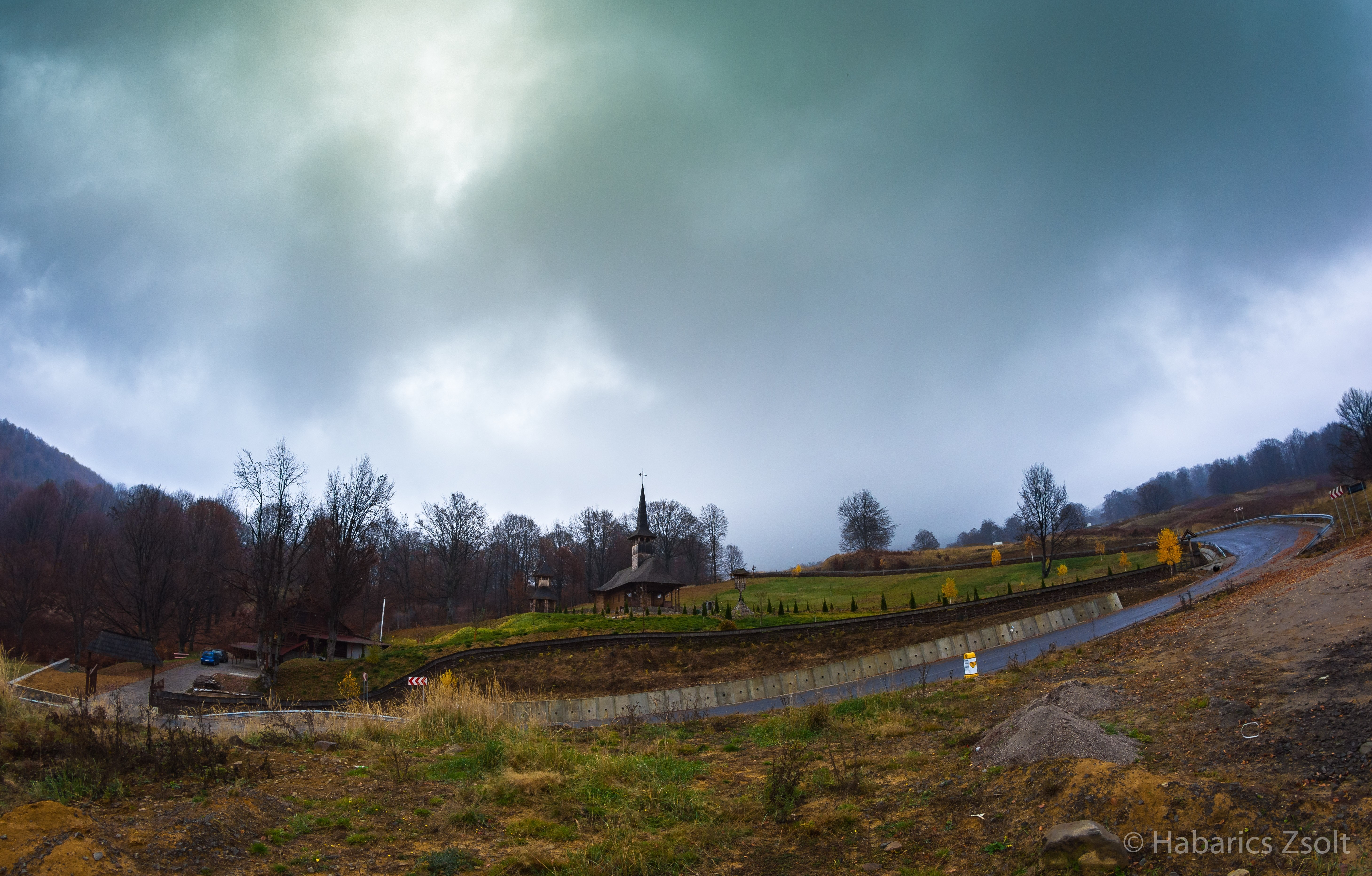 Wooden church on a hill with a winding road HD Wallpaper