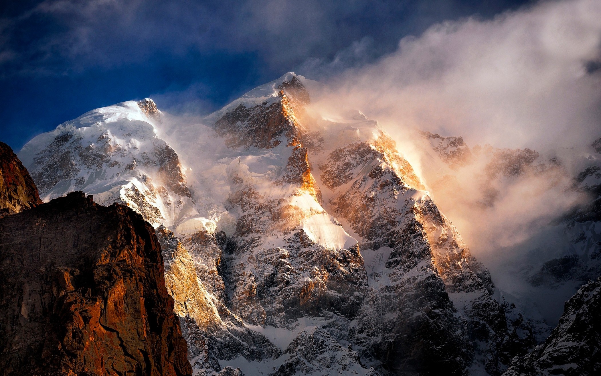 Sunlight on a snowy mountain peak with clouds HD Wallpaper