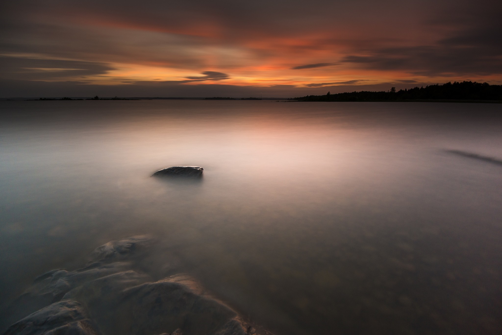 Sunset over a calm body of water with a rock HD Wallpaper