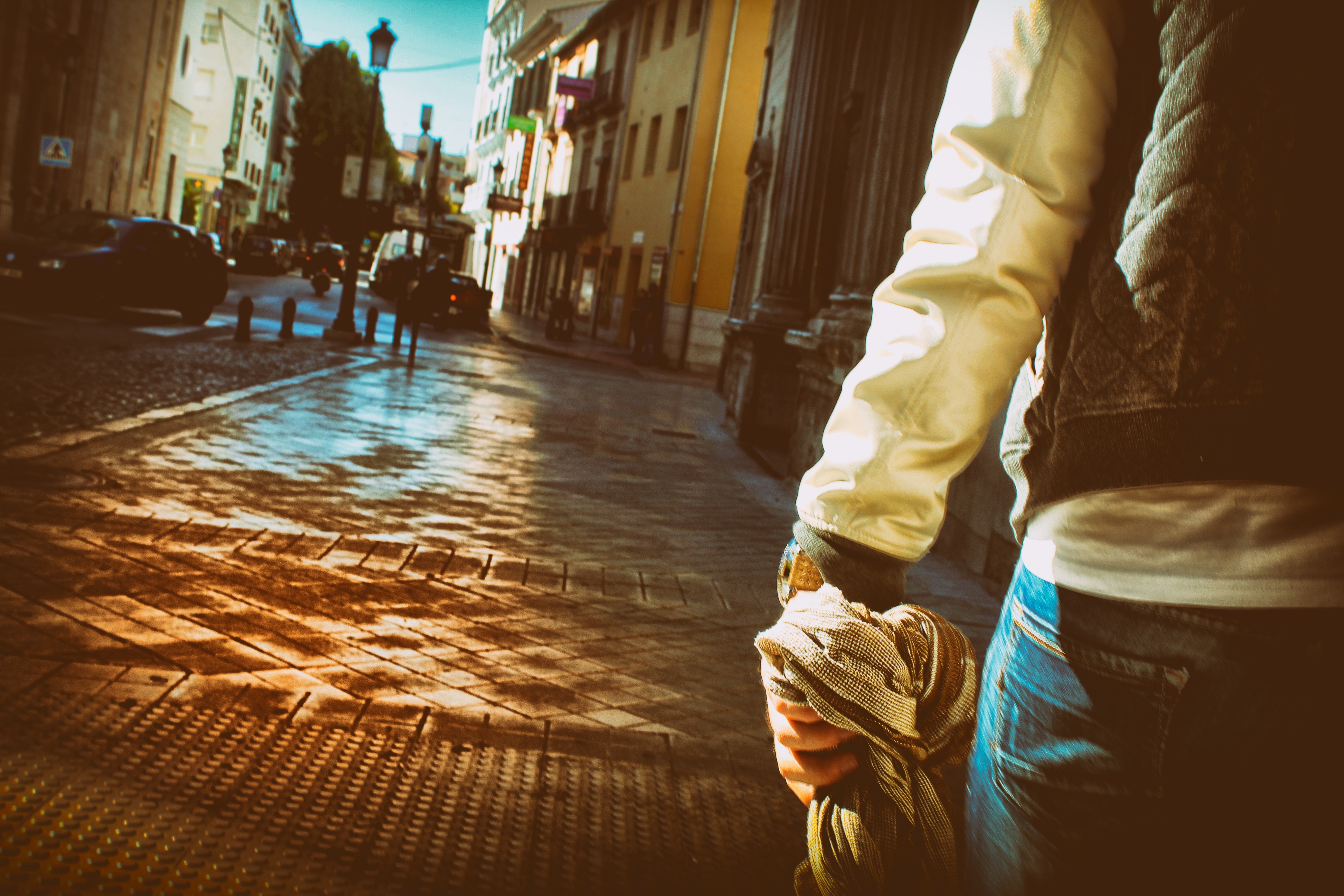 Person walking down a sunlit street in a city HD Wallpaper