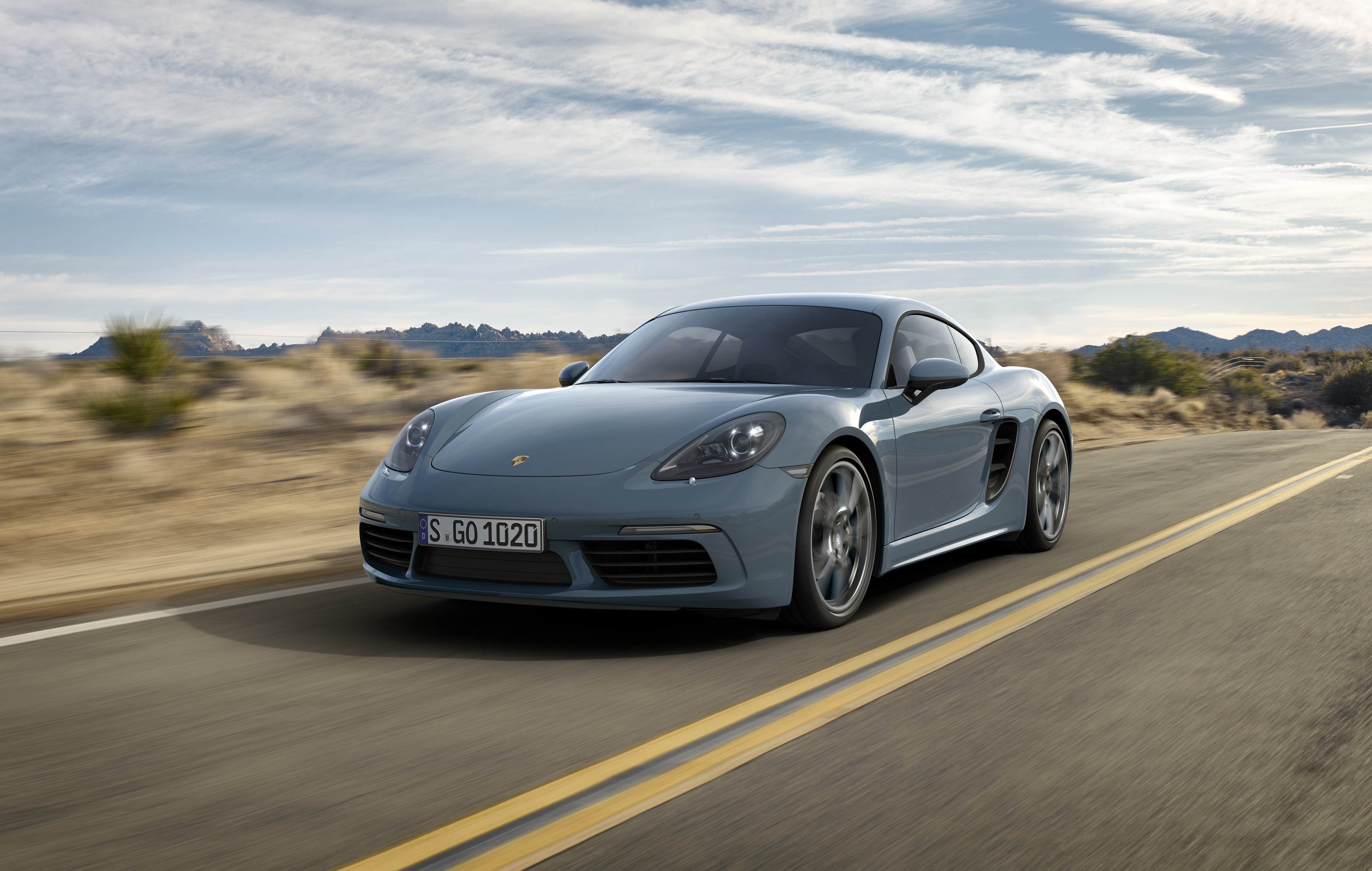 Grey Porsche 718 Cayman driving on a desert road HD Wallpaper