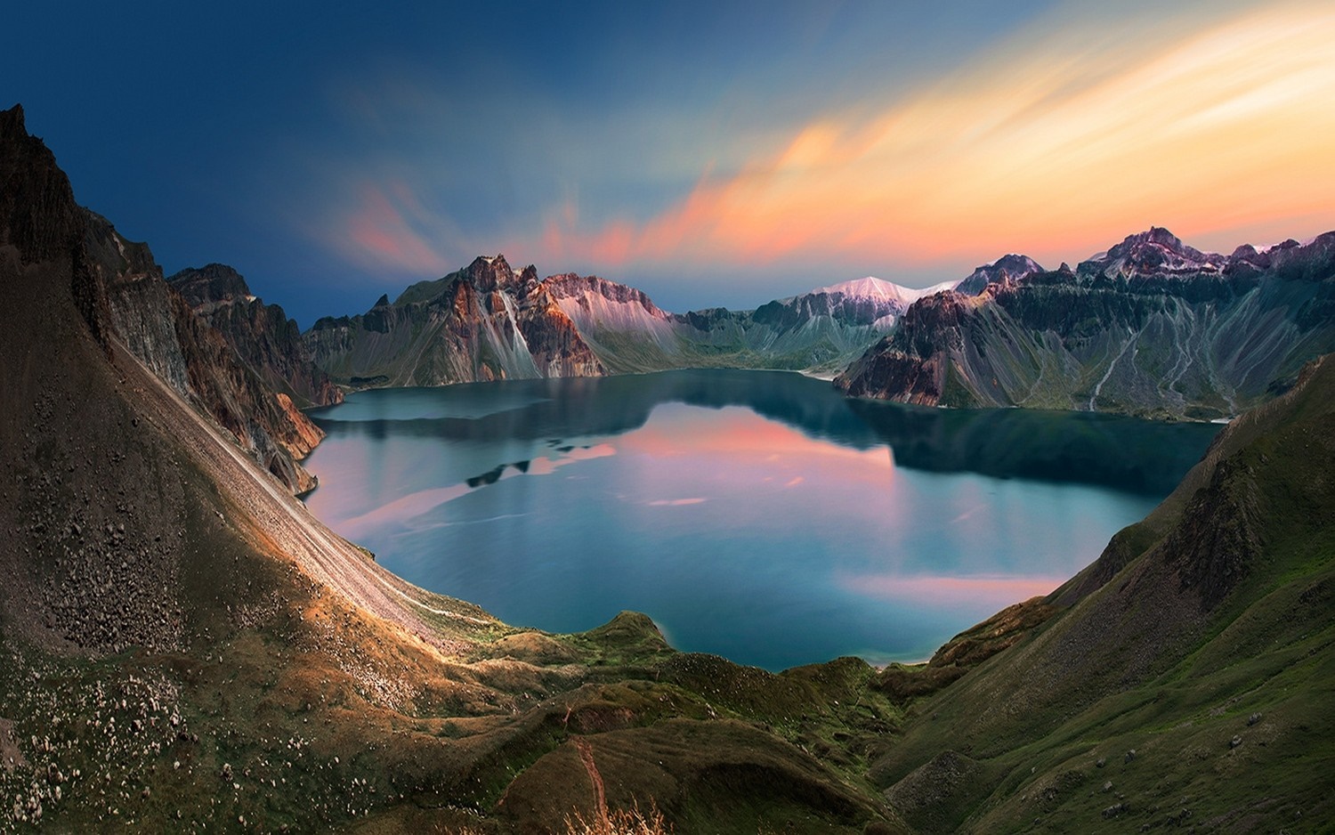 Crater lake surrounded by mountains at sunset HD Wallpaper