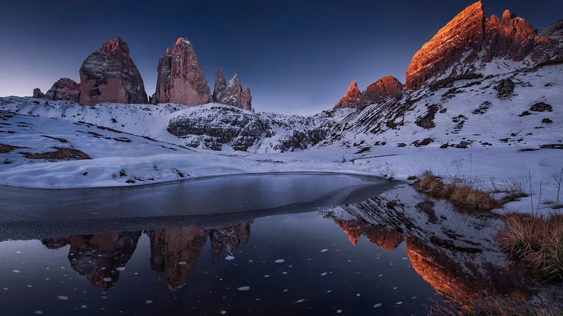 Snowy mountains reflecting in a frozen lake at dawn HD Wallpaper