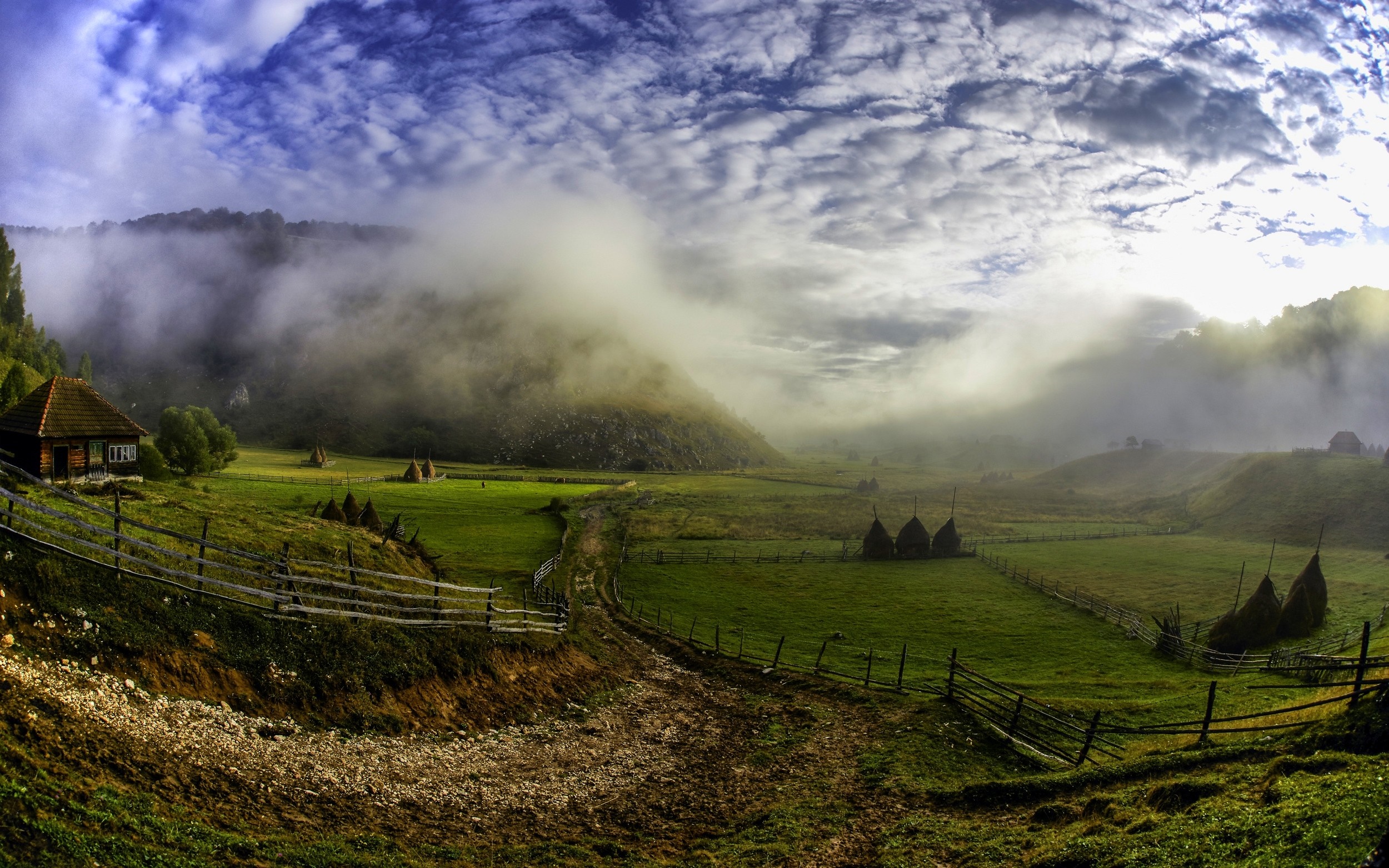 Misty morning in a Romanian rural landscape with haystacks HD Wallpaper