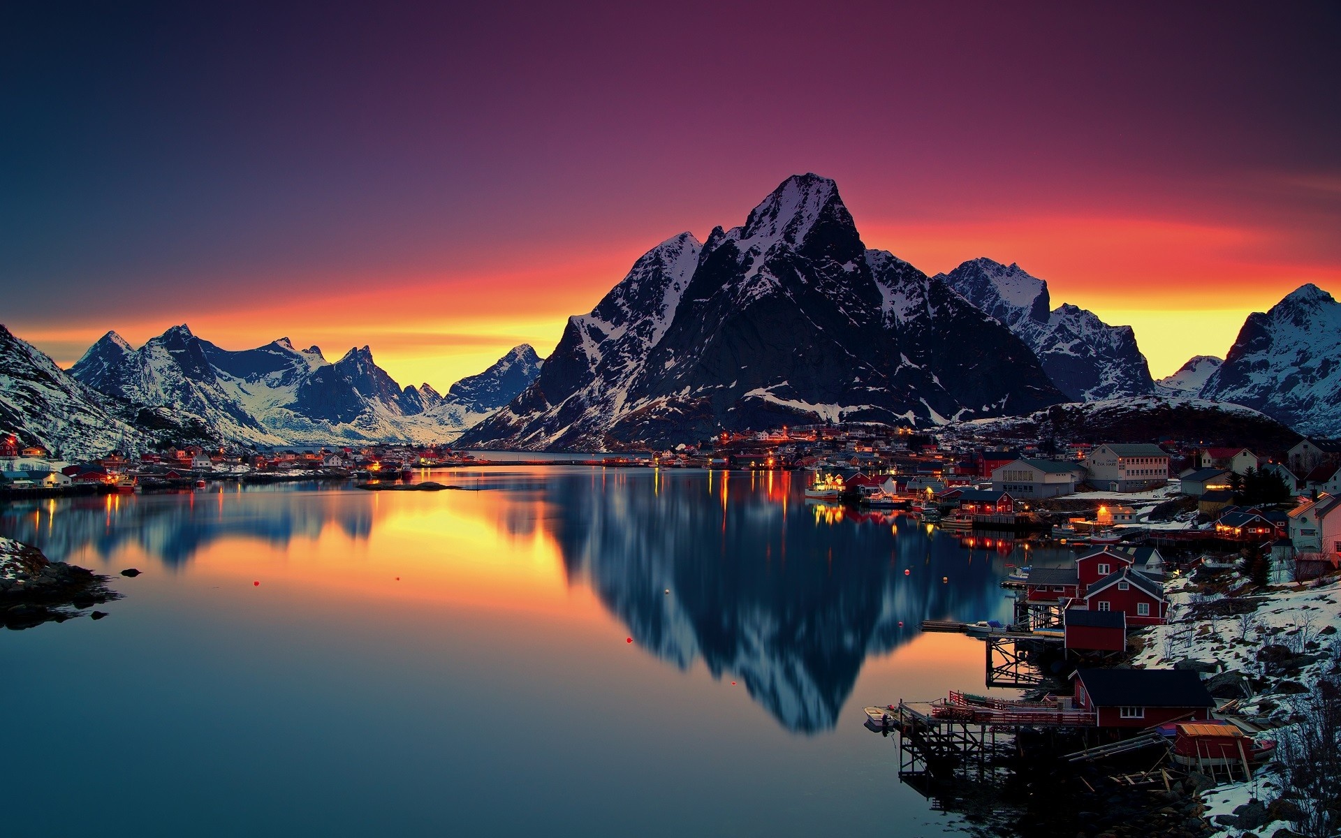 Snowy mountains and village at sunset over water in Lofoten, Norway HD Wallpaper