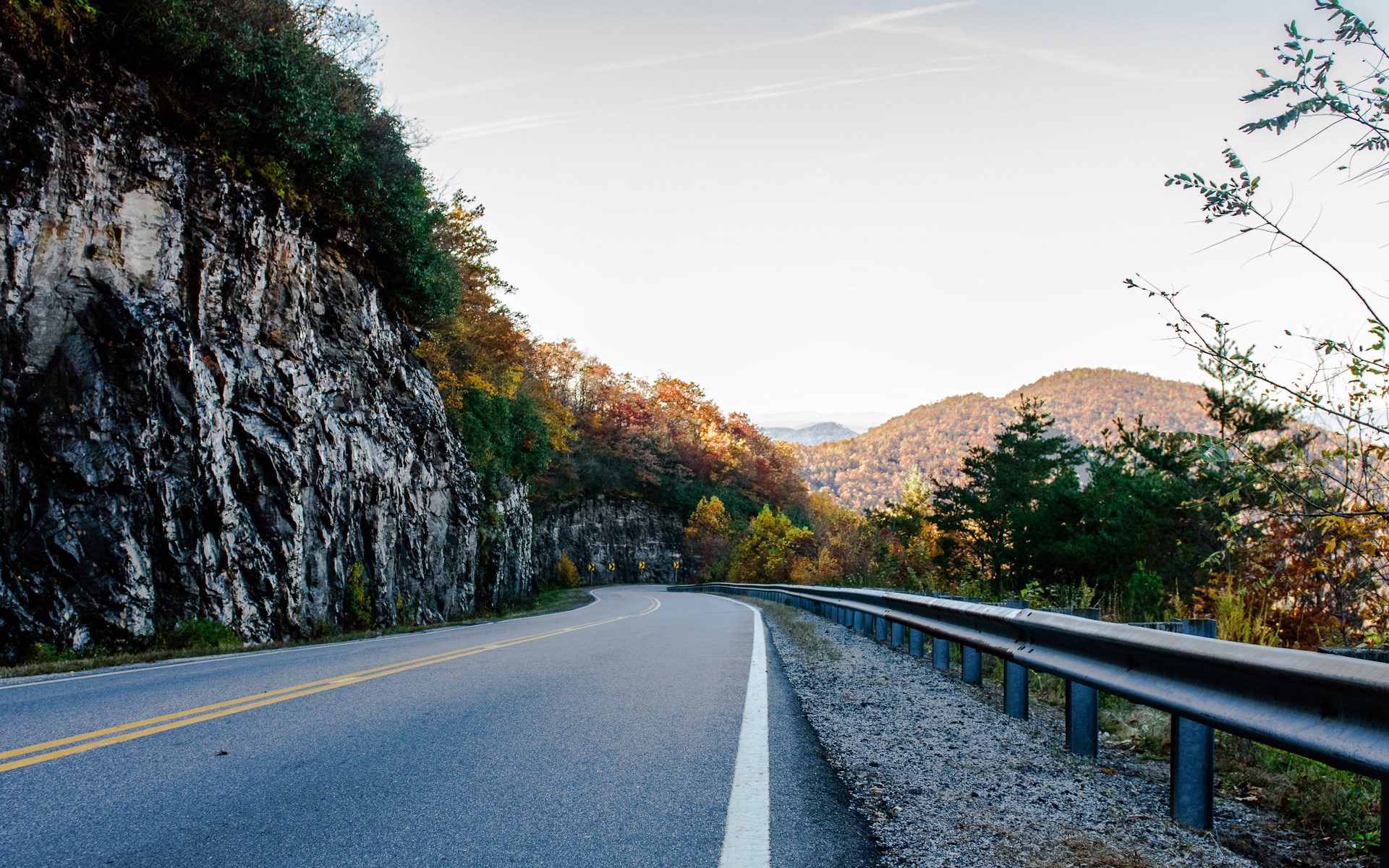 Mountain road with guardrail and autumn foliage HD Wallpaper