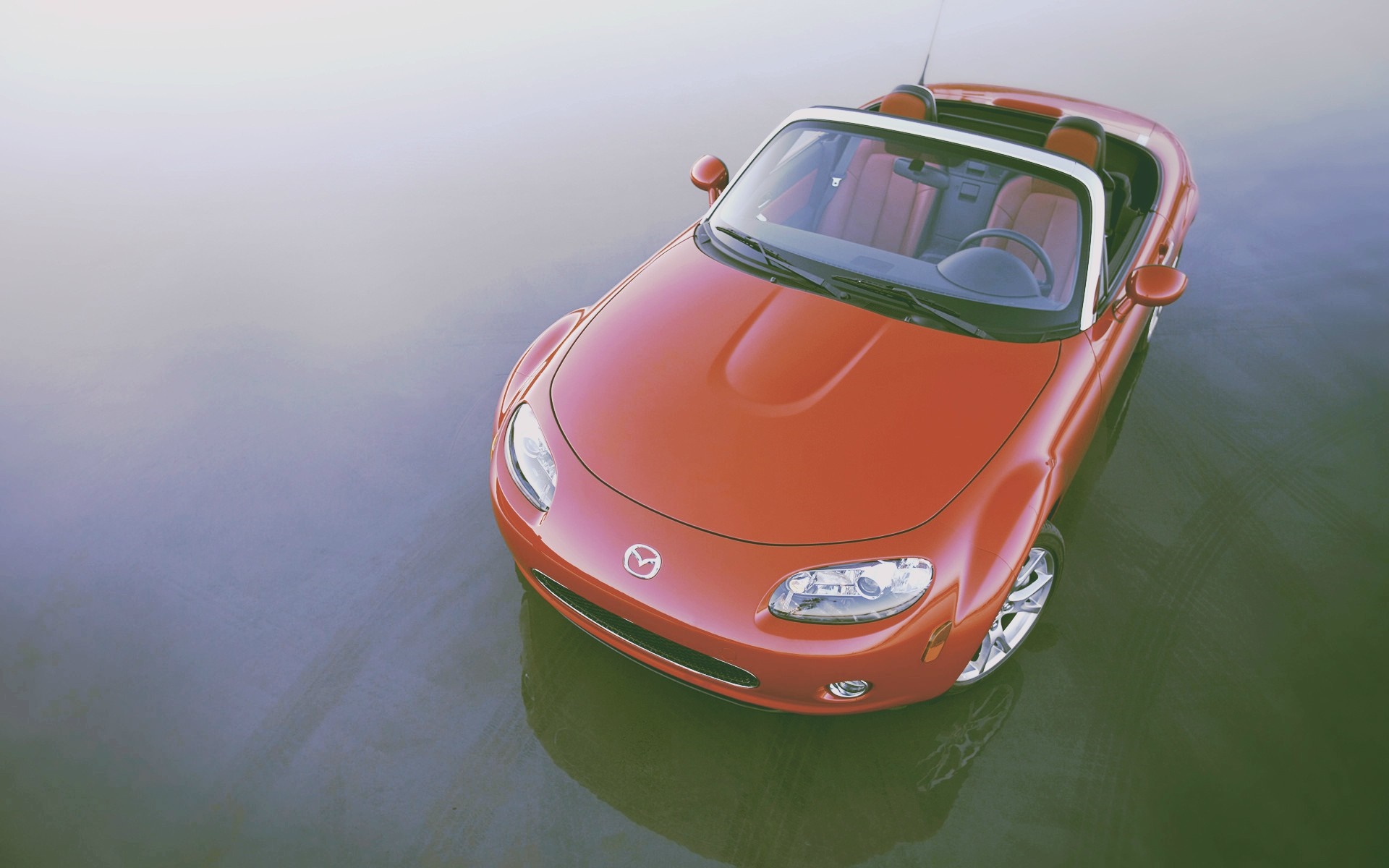 Red Mazda MX-5 convertible parked on a reflective surface HD Wallpaper