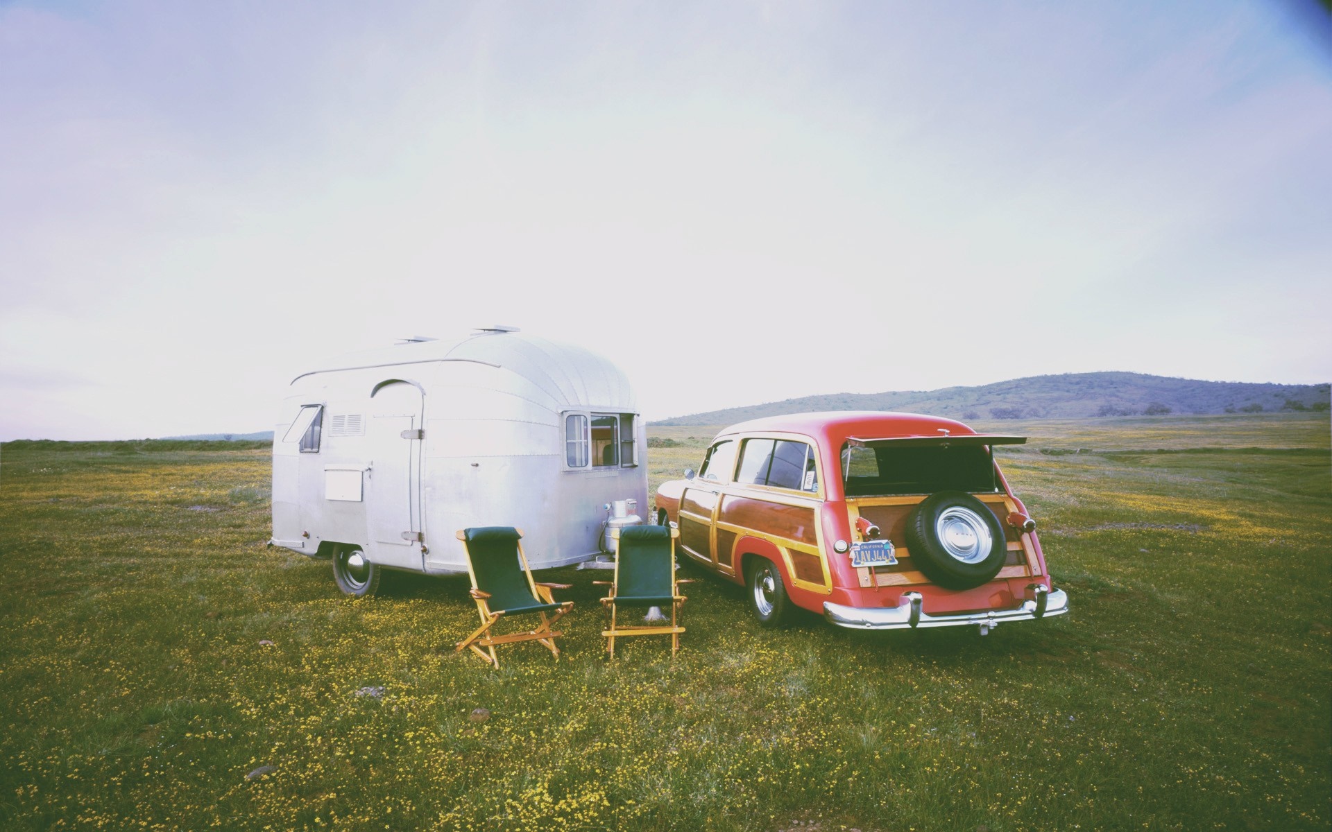 Vintage Airstream trailer and woody station wagon in a field HD Wallpaper
