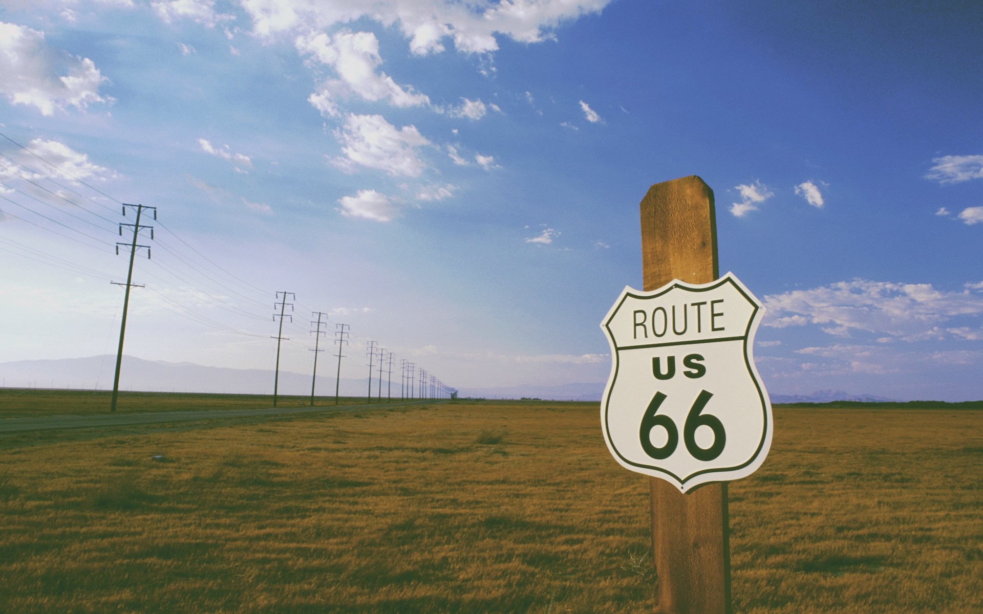 Route 66 sign in a vast grassy plain with power lines HD Wallpaper