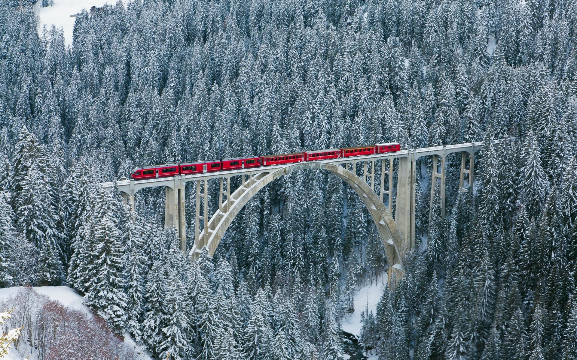 Red train on a snowy bridge in Switzerland HD Wallpaper