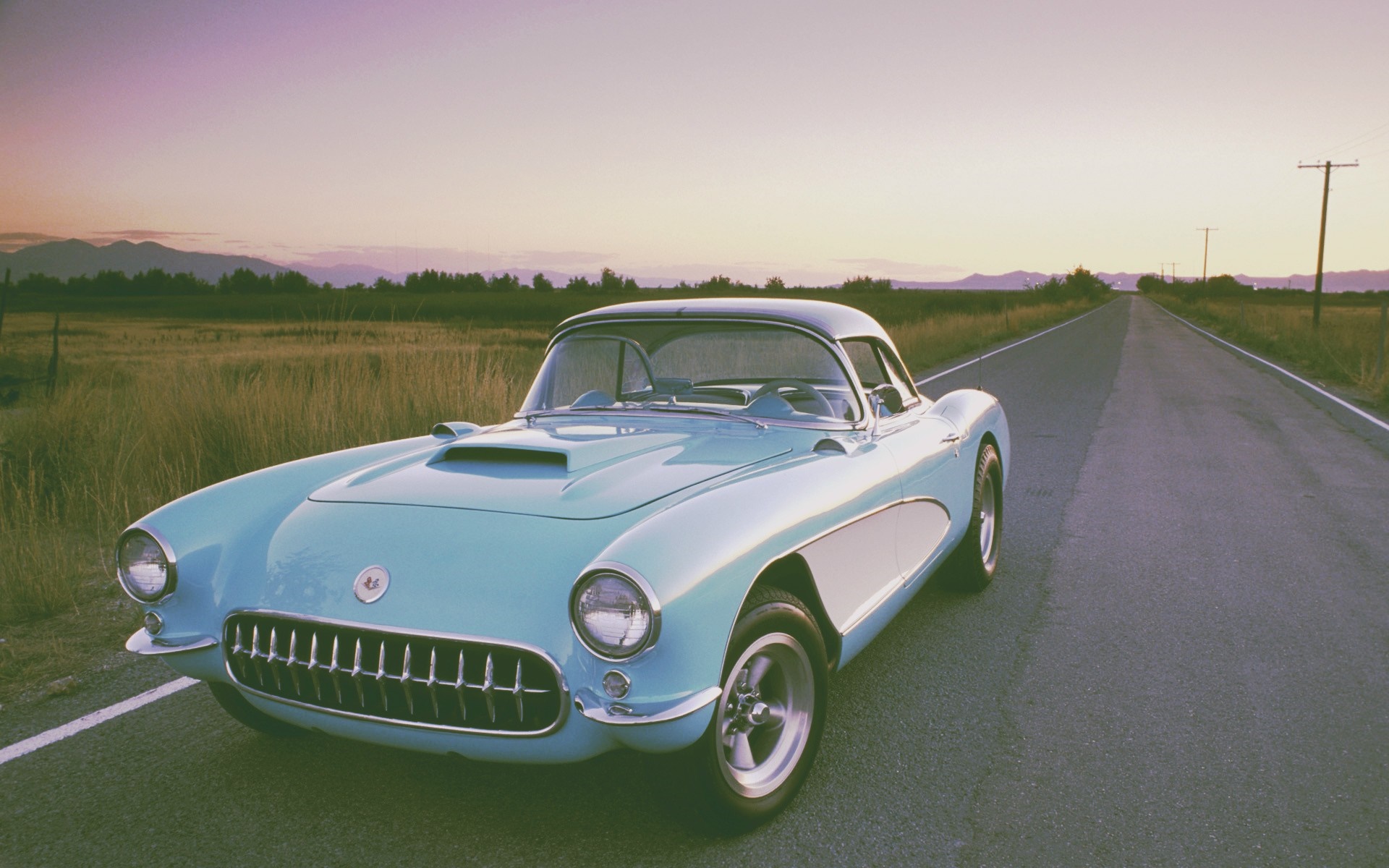 Vintage light blue Chevrolet Corvette on a rural road at sunset HD Wallpaper