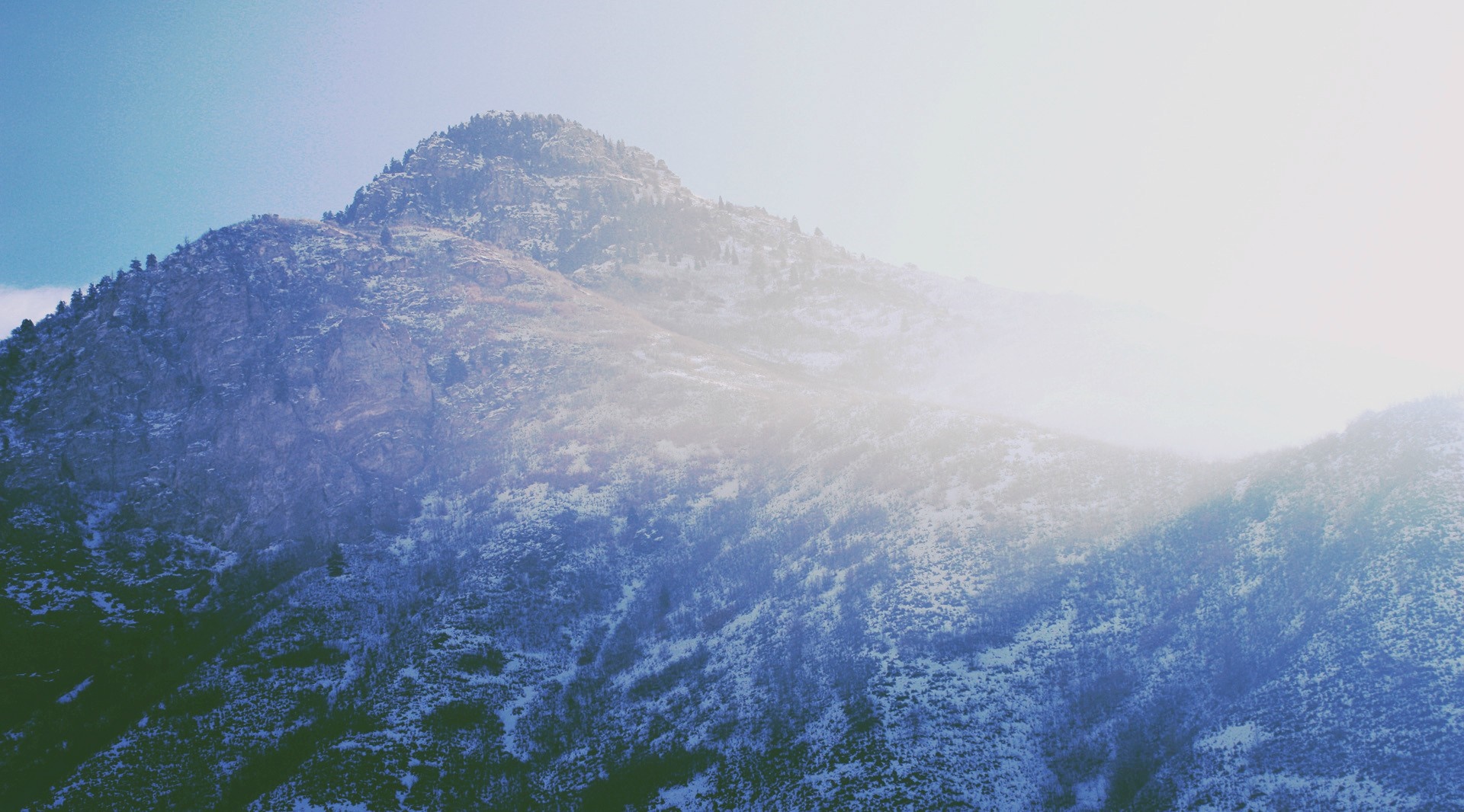 Snow-covered mountain peak with sunlight and mist HD Wallpaper