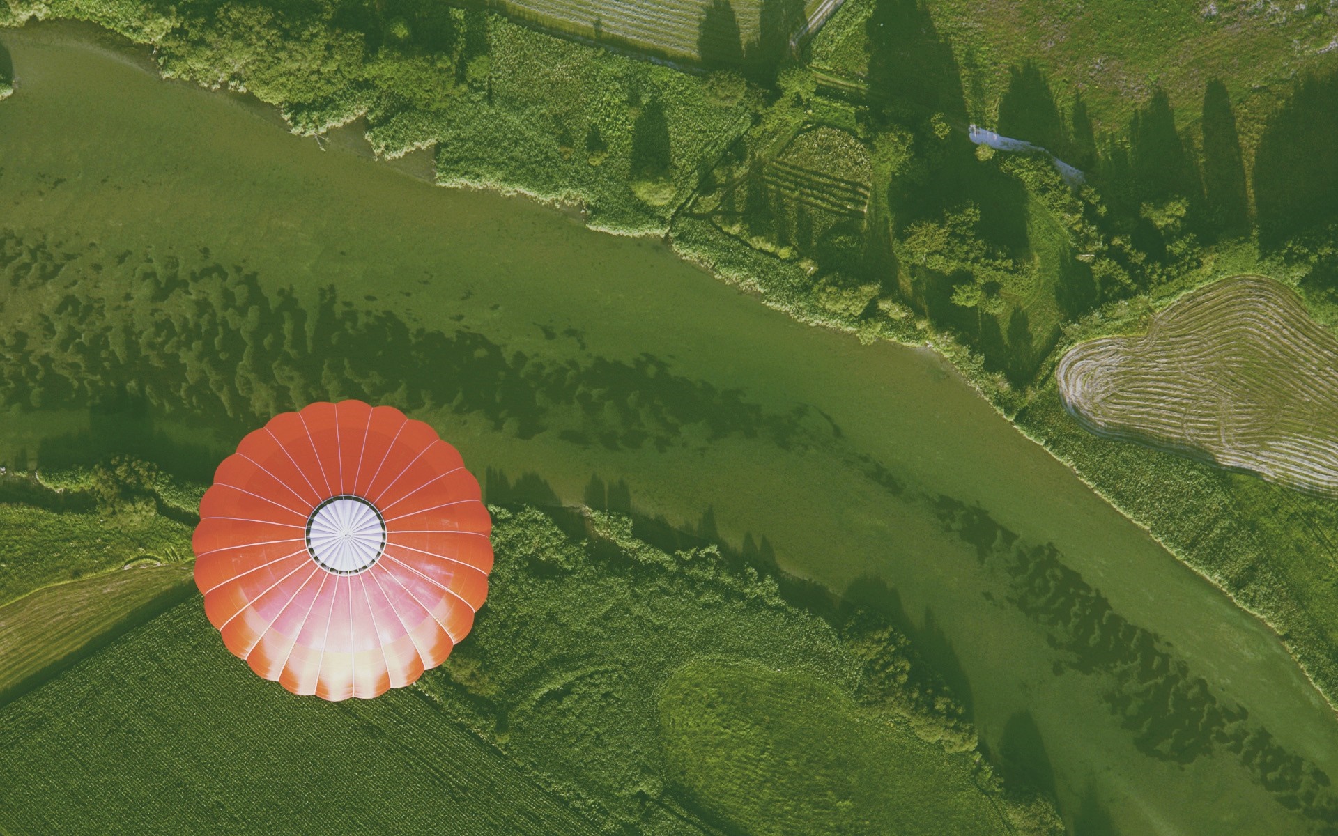 Red hot air balloon over green fields and river HD Wallpaper